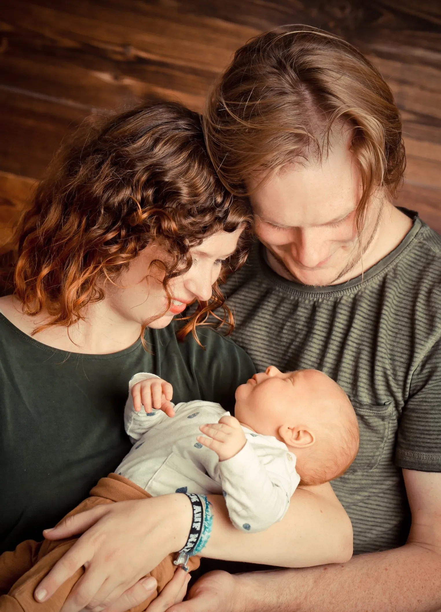 Newbornfotoshooting im Fotostudio in Darmstadt. Familie mit einem neugeborenen Baby, die zusammen eng umarmt und liebevoll schaut.