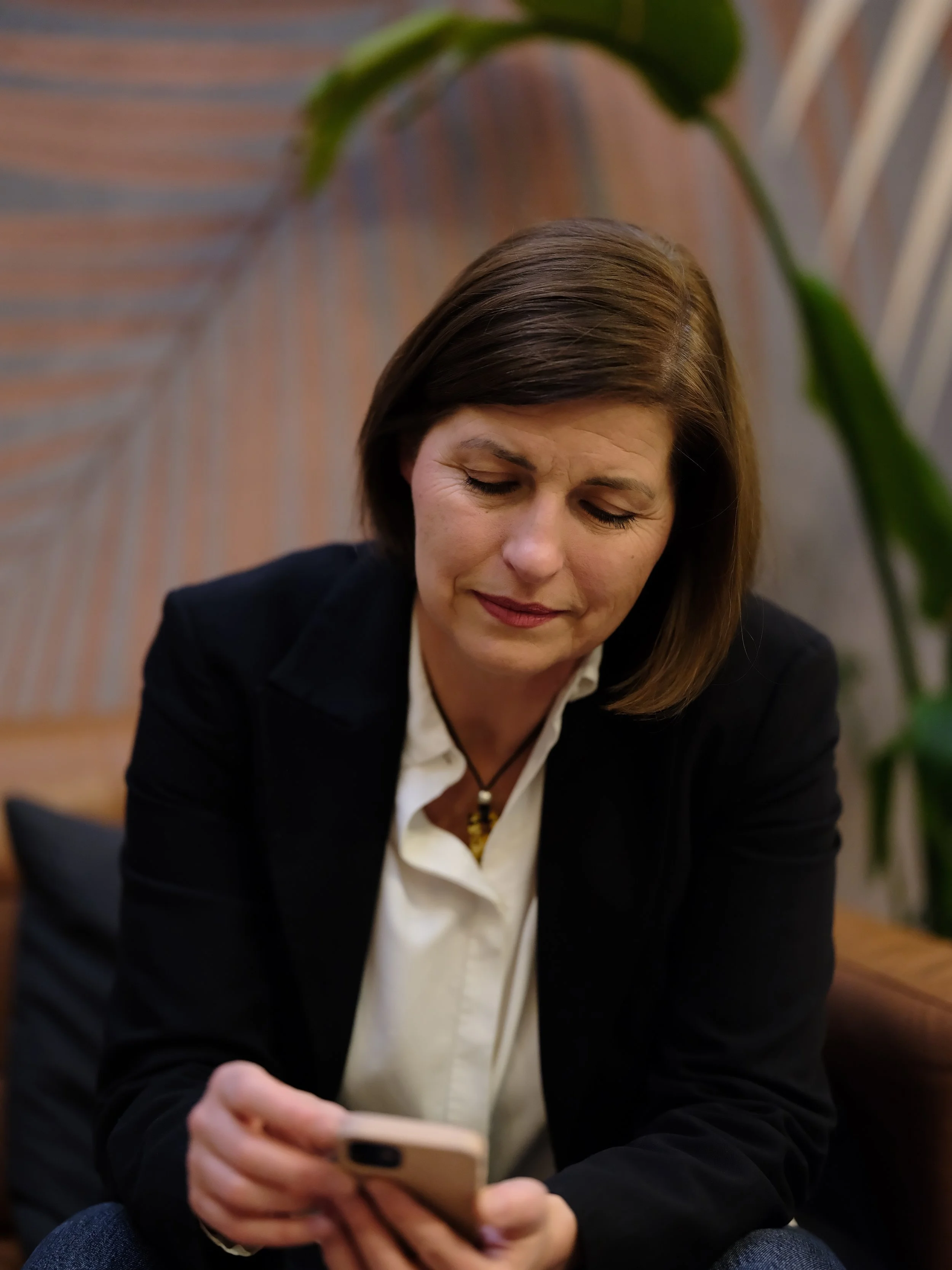 Coachery ül egy kanapén és a mobiltelefonját nézi.