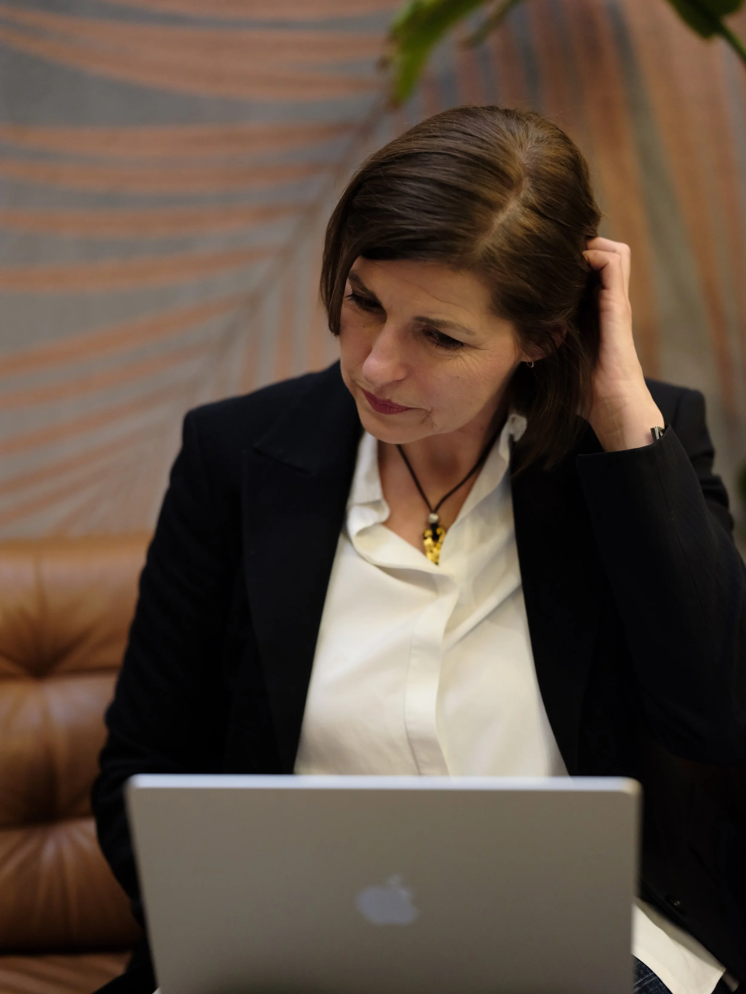 coachery ül egy kanapén egy kávéházban, az ölében laptop és a hajába túr, úgy gonsolkozik