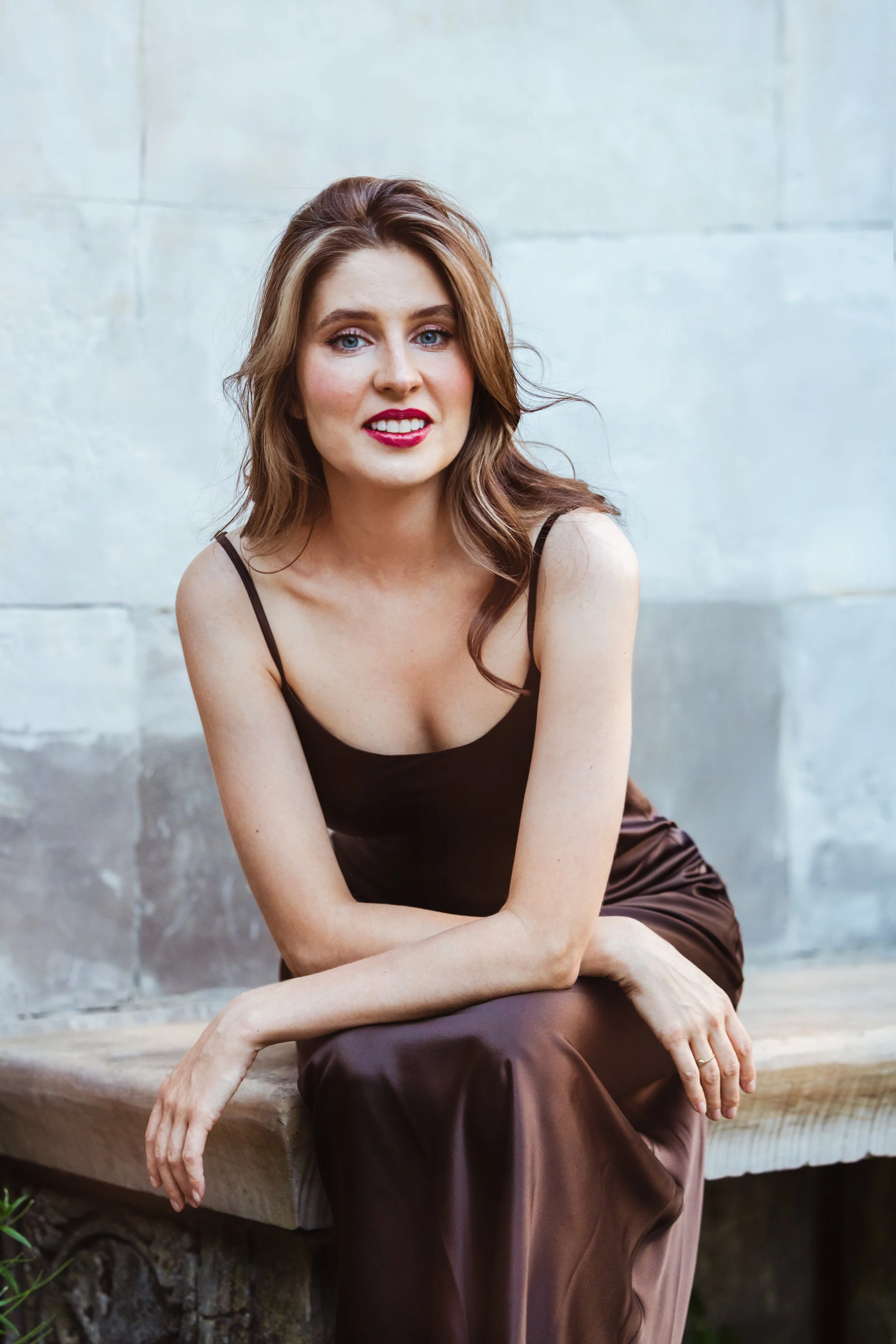 Anna Koźlakiewicz, śpiewaczka operowa, portret w brązowej sukience na kamiennej ławce
