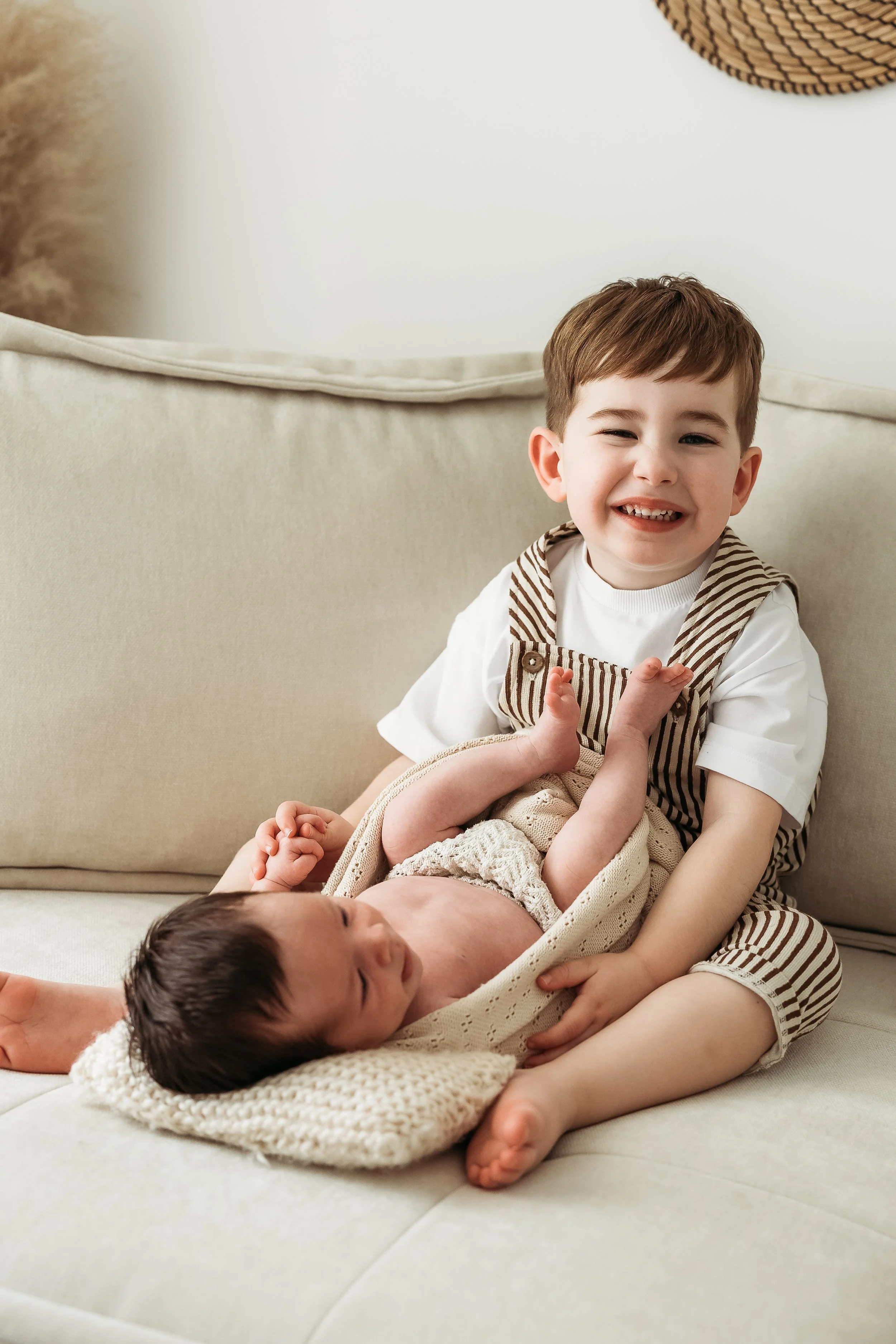 Older sibling meeting and cuddling their newborn baby during a relaxed newborn photography session.