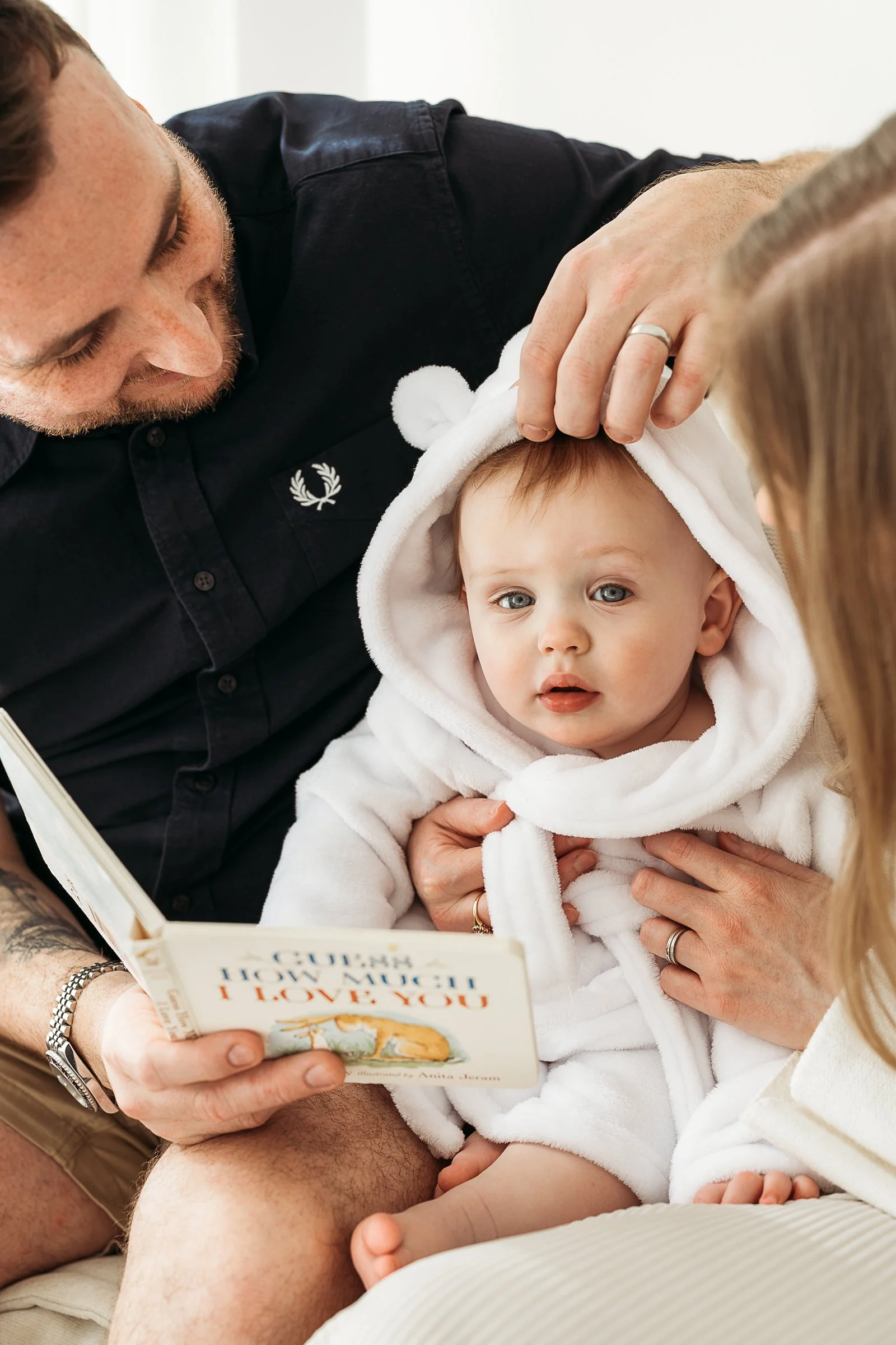 Father reading a story book to his toddler during a relaxed first birthday photography session.