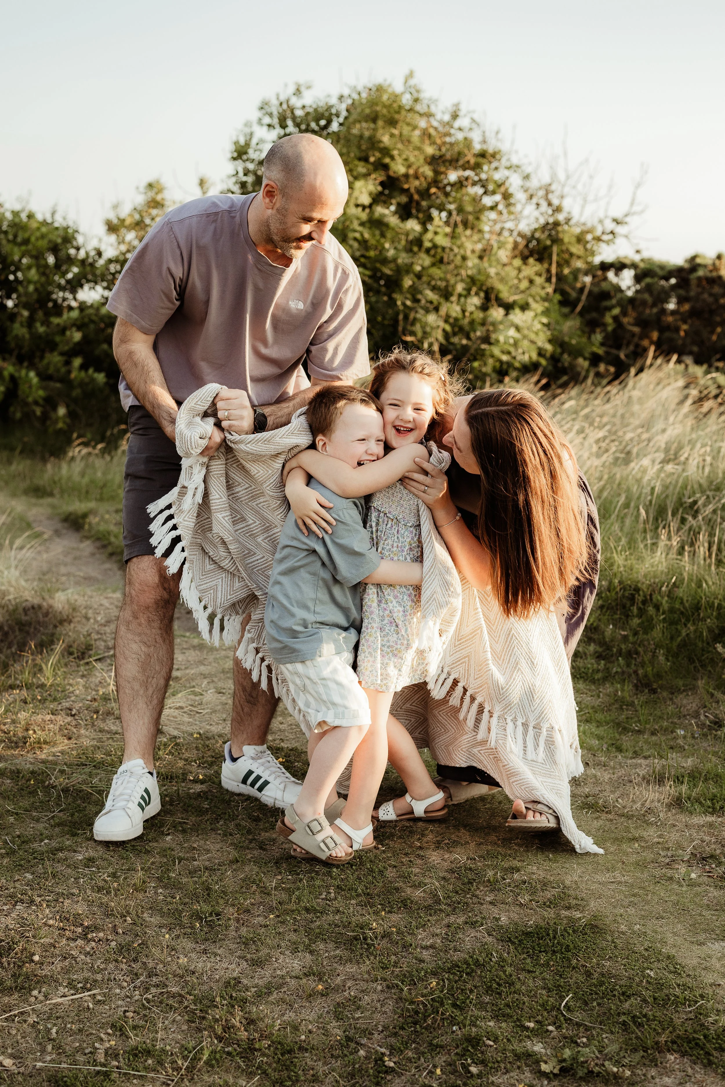 A family of five sharing laughter, cuddles and connection outdoors, preserving the little moments that make family life so special.