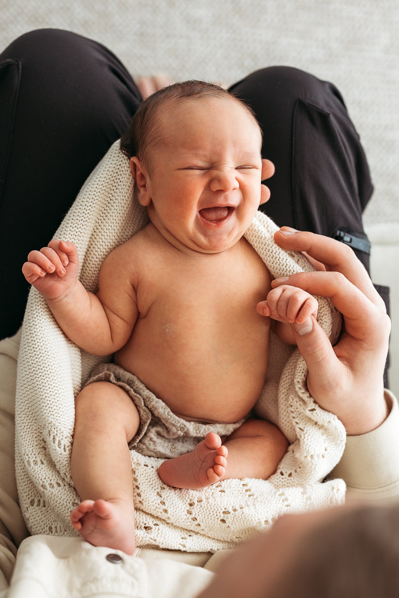 Newborn baby sharing a joyful moment with parents during a natural newborn photography session.