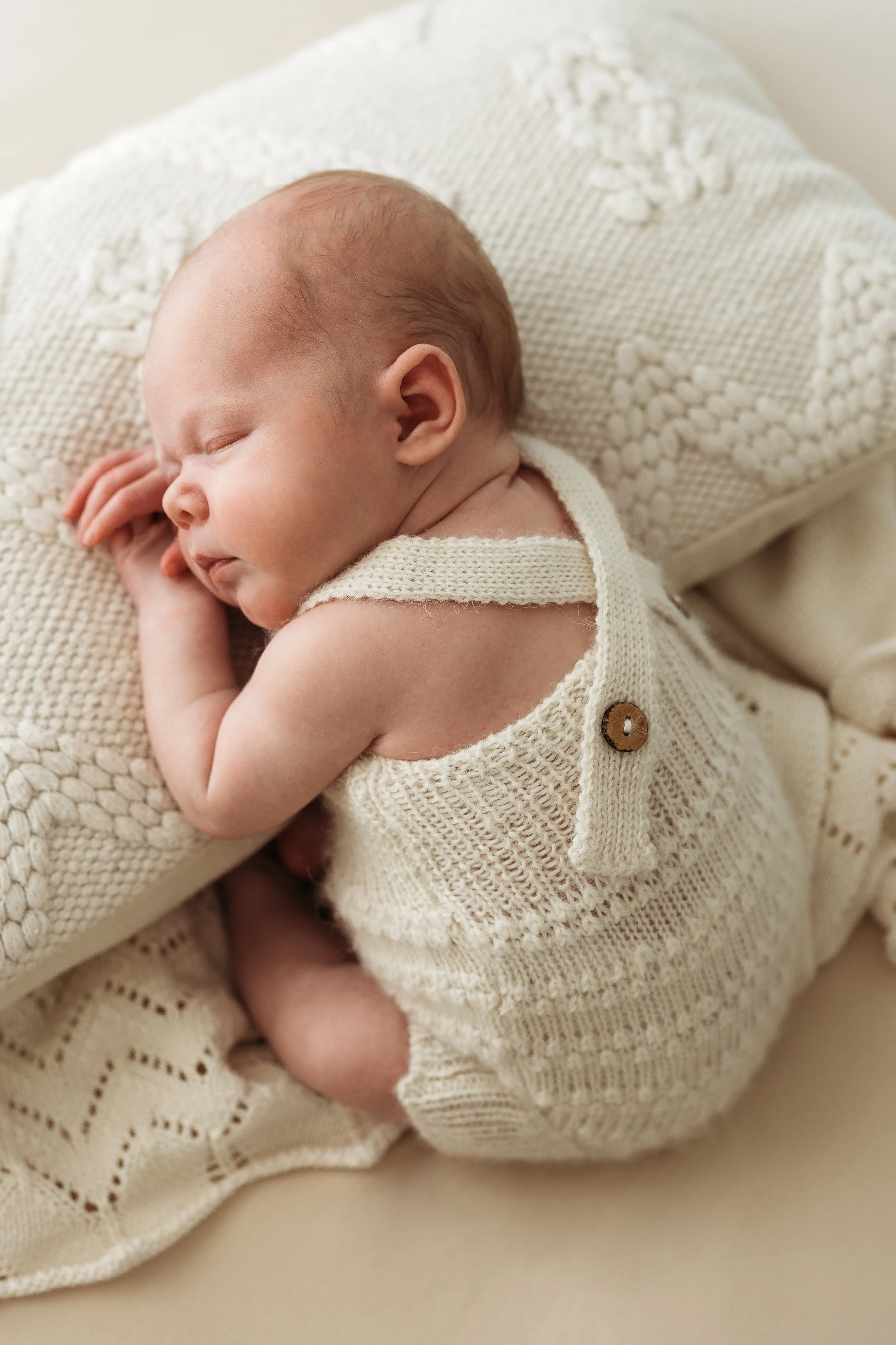 Sleeping newborn baby wrapped in a soft blanket during a natural newborn photography session.