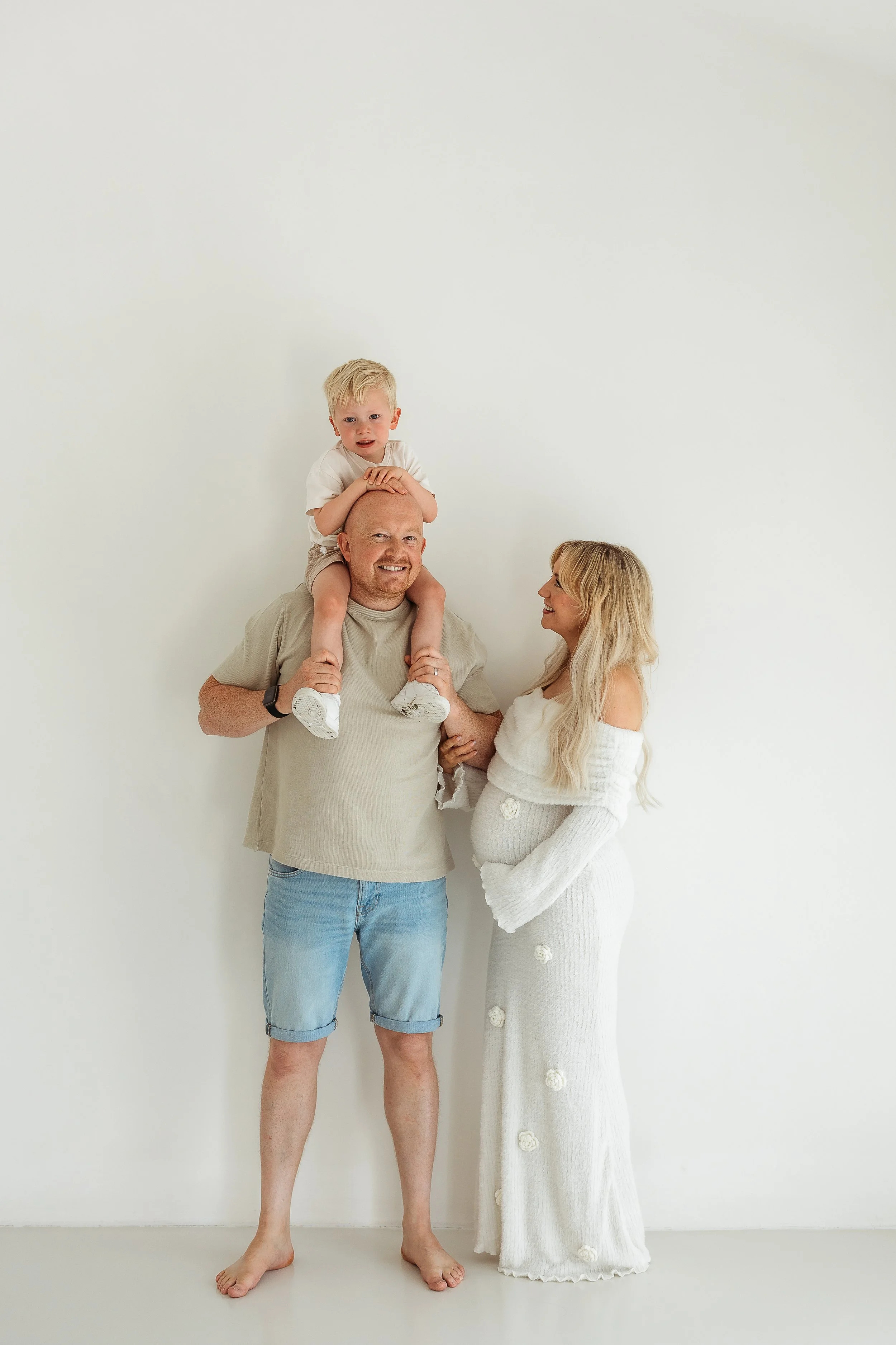 A family sharing a joyful moment together during a maternity photography session before welcoming a new baby.