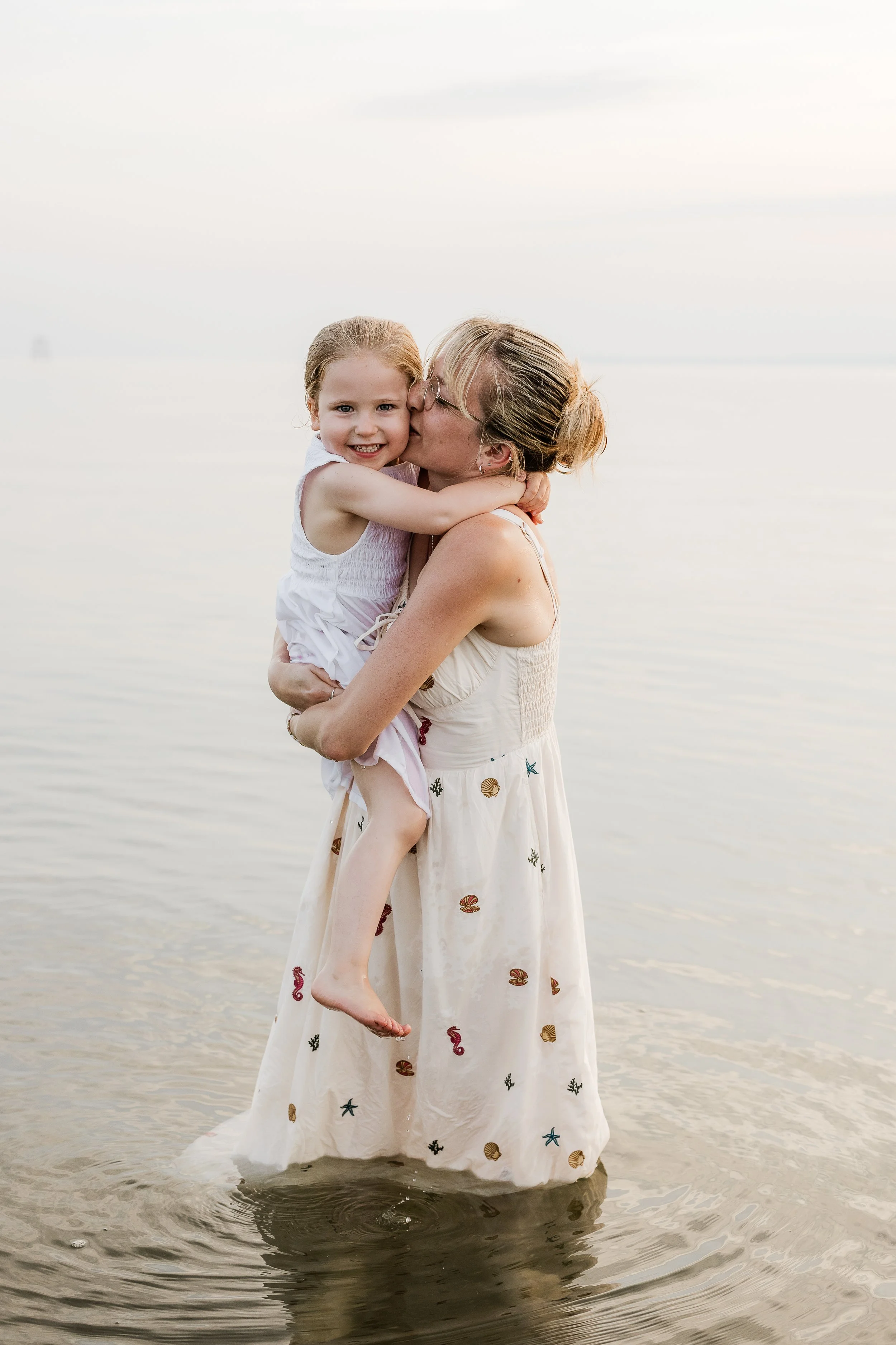 A mother and daughter embracing in the ocean, capturing their bond, joy and the beautiful connection between them.