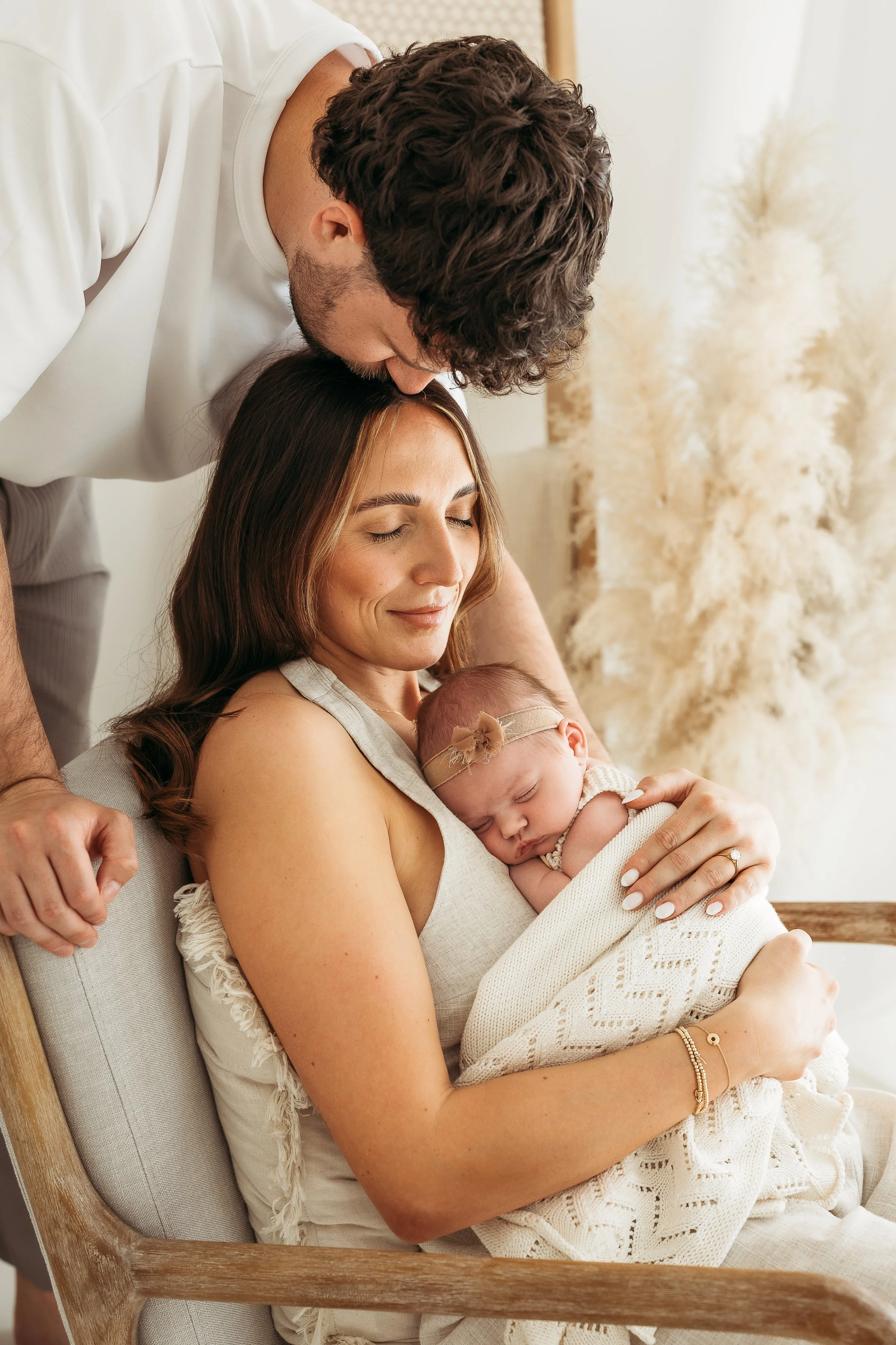 Parents cuddling their newborn baby during a relaxed newborn photography session.