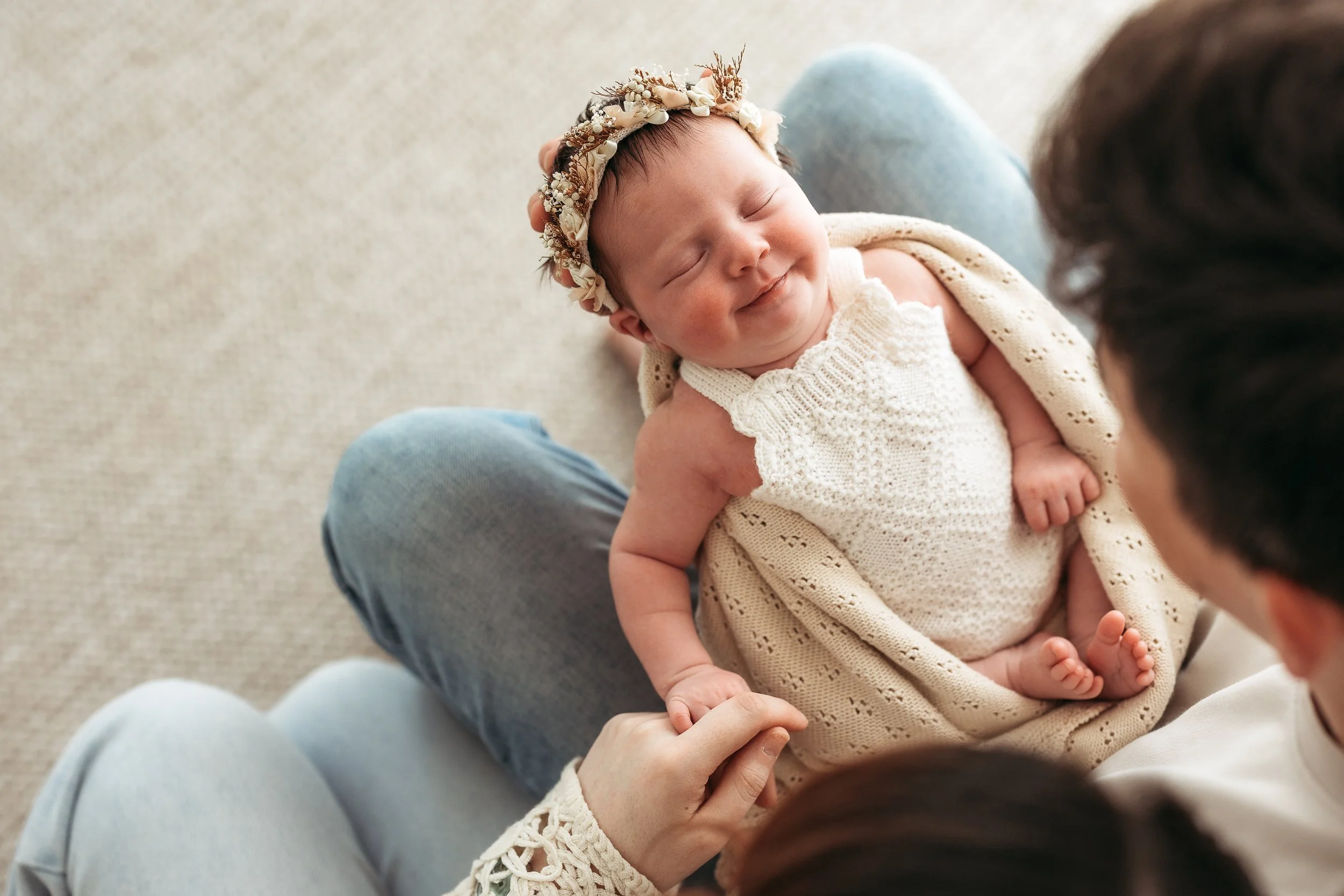 Sleeping newborn baby girl being held during a relaxed newborn photography session.