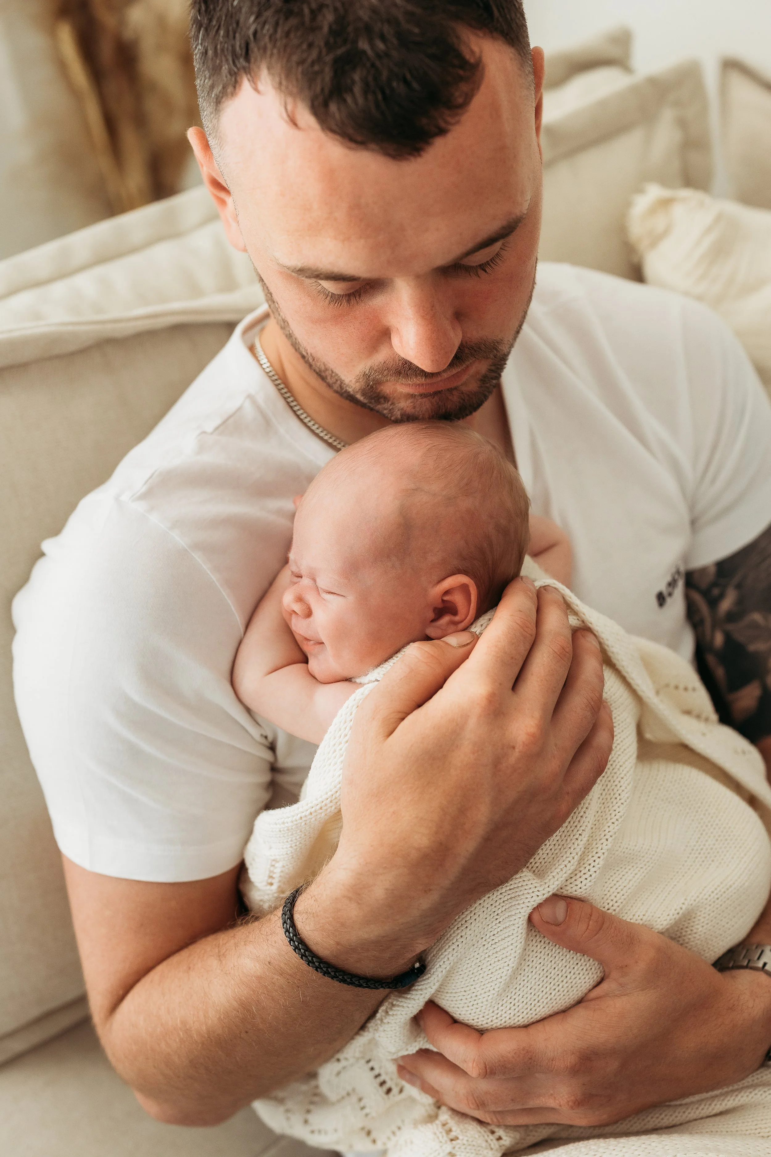 Father gently cuddling his newborn baby during a relaxed newborn photography session.