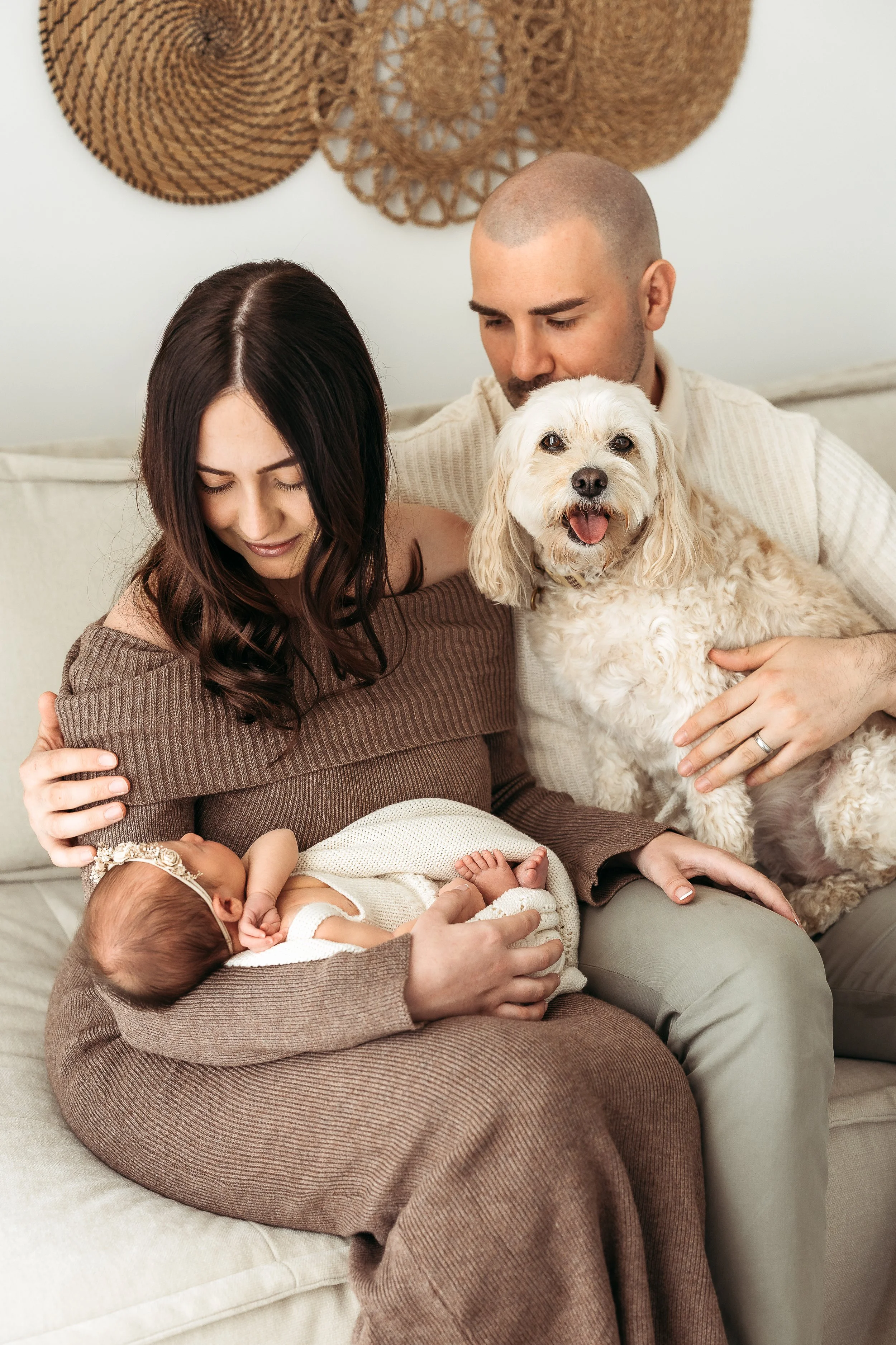 Mother cradling her newborn baby while capturing the love and connection of the whole family, including their dog.