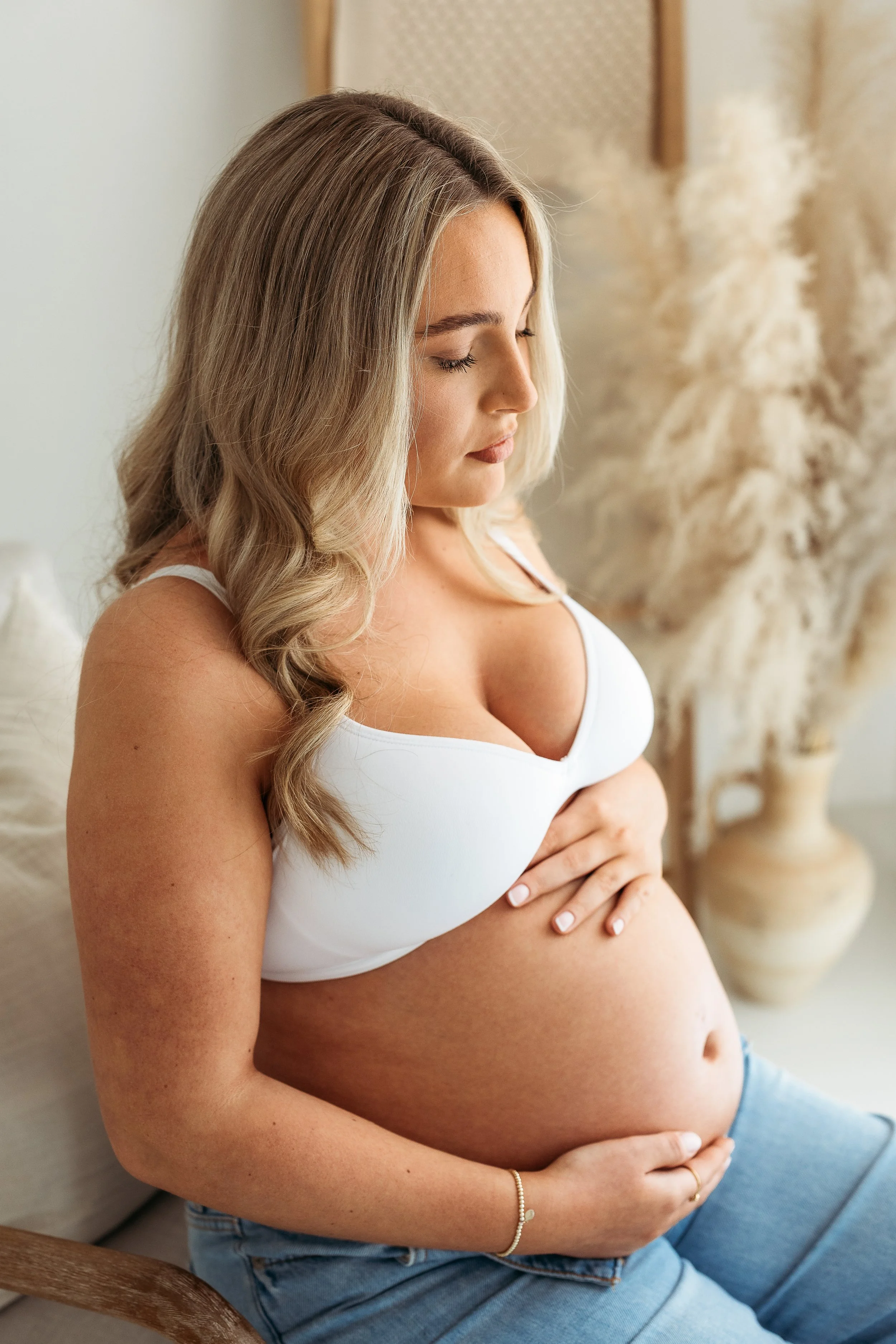 A mother-to-be taking a quiet moment to connect with her baby bump during a natural maternity photography session.