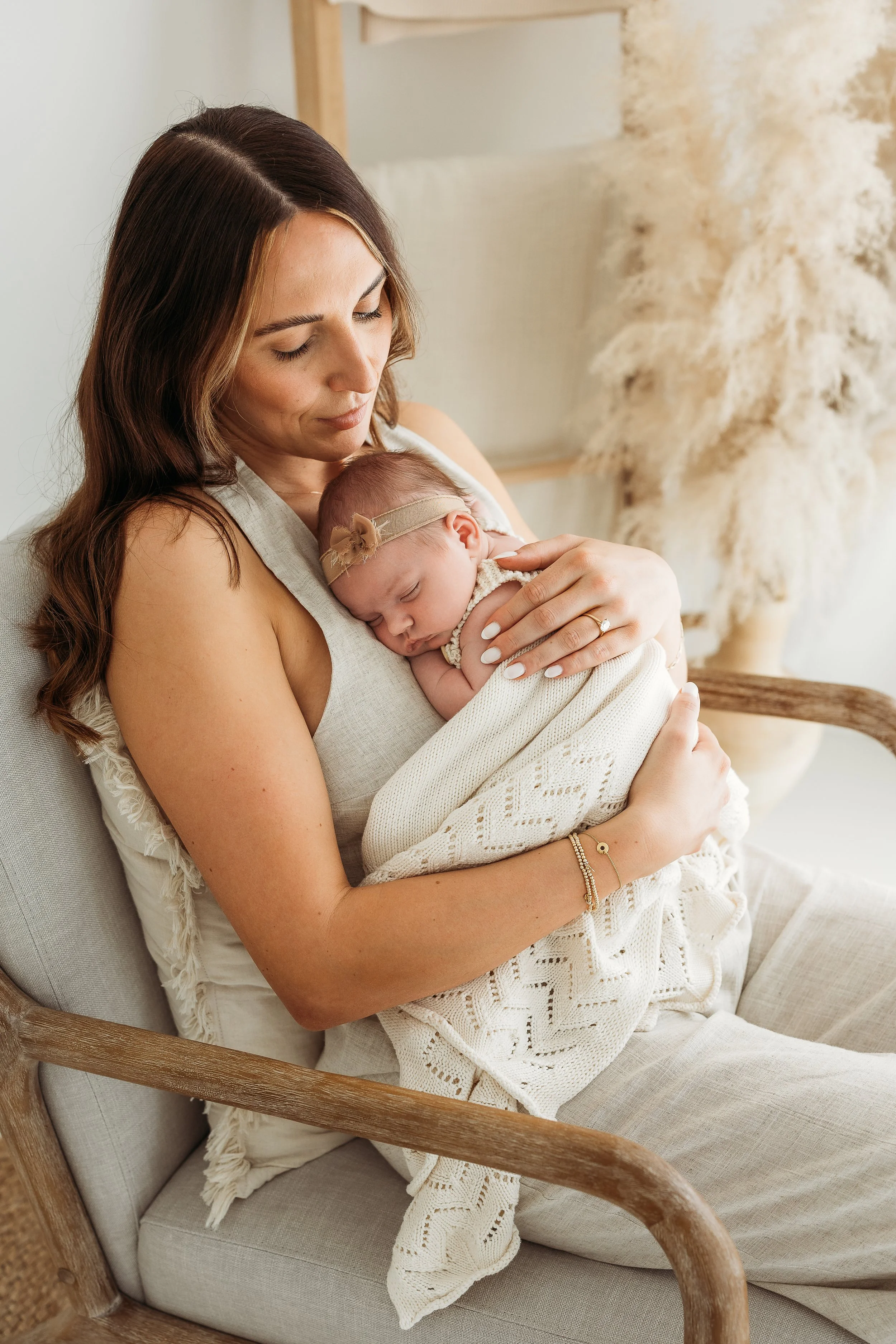 Mother holding her newborn baby during a calm, connection-focused newborn photography session.