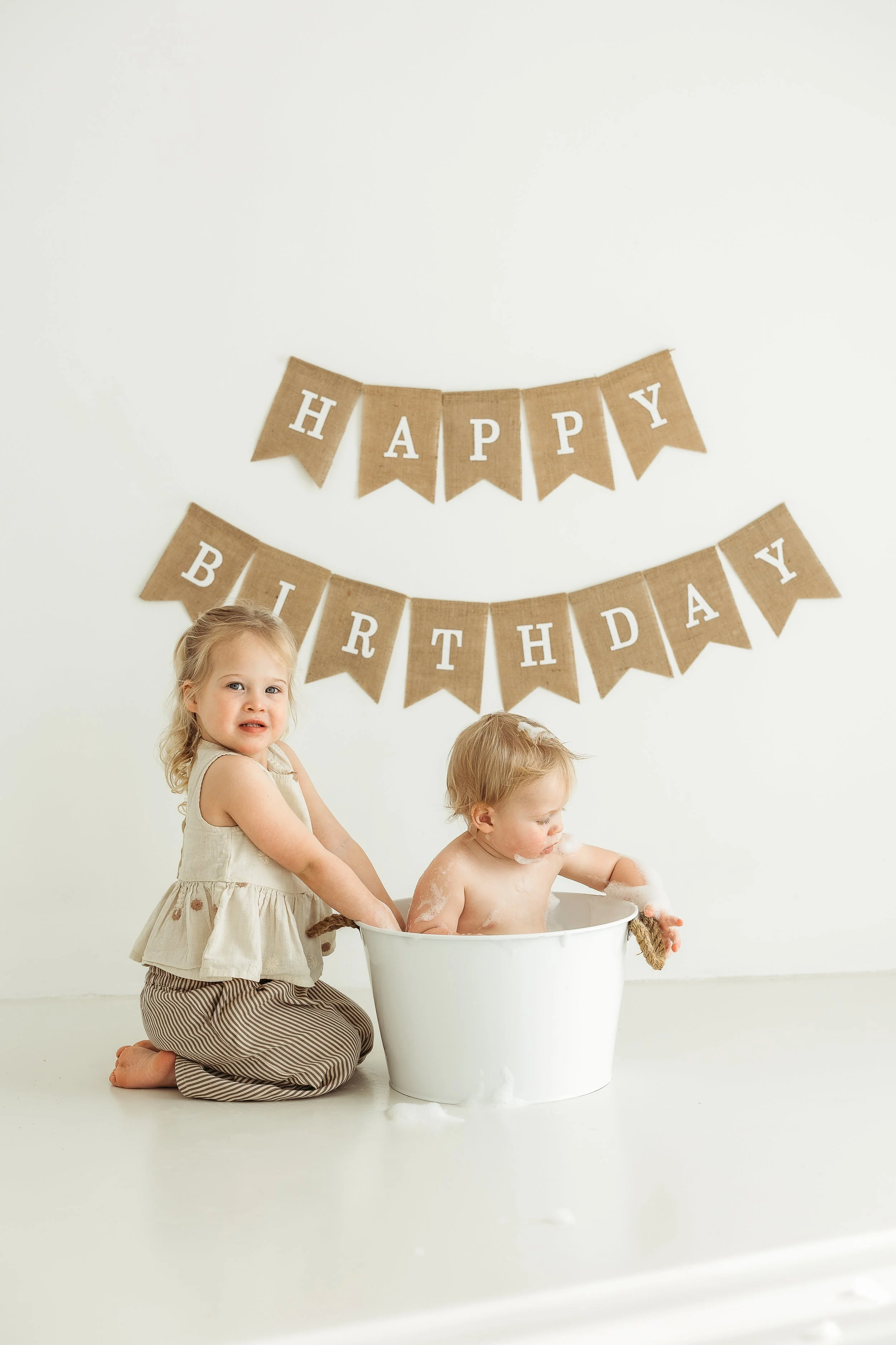 Siblings enjoying a playful birthday bath moment, capturing laughter, connection and the fun of childhood.