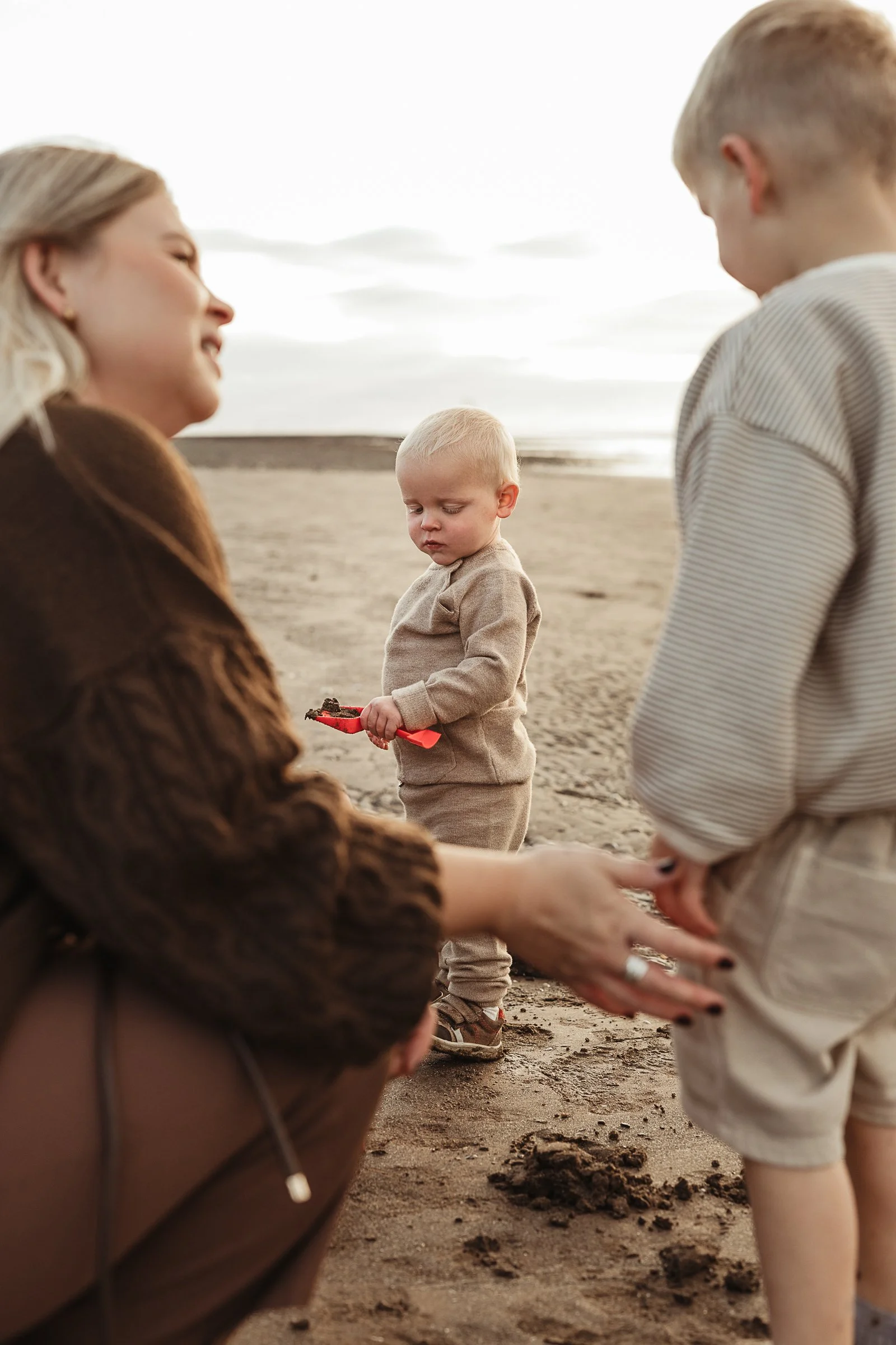 A family enjoying a playful moment together on the beach during a relaxed outdoor family photography session.