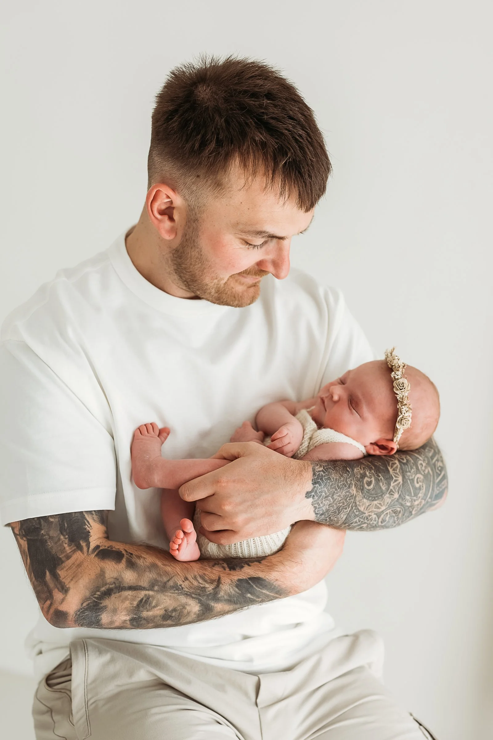 Father gently cuddling his newborn baby during a relaxed newborn photography session.