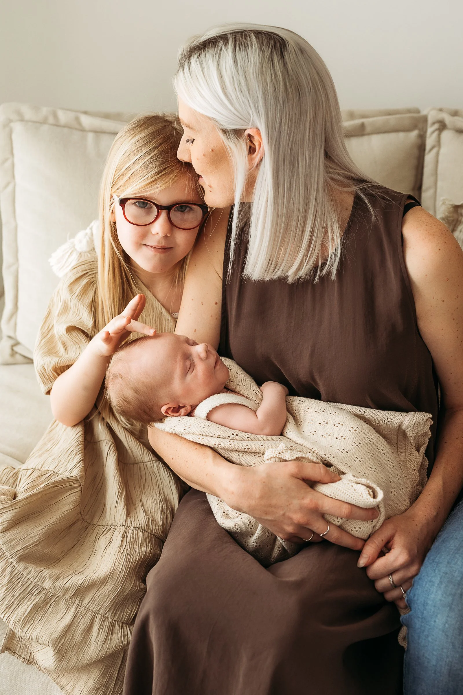 Mum and sibling sharing a quiet moment with a newborn baby during a relaxed newborn photography session.
