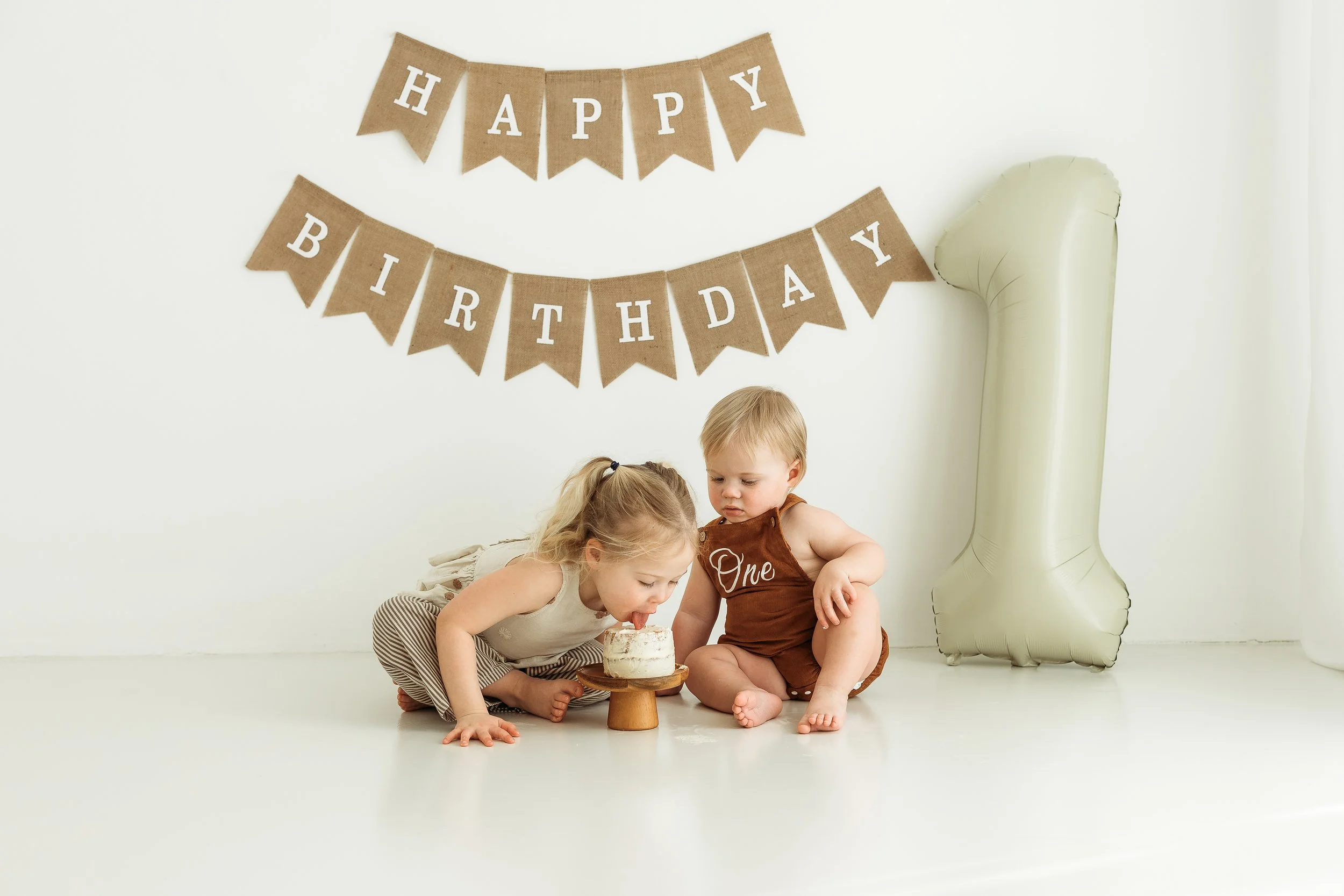 A sweet first birthday moment with a sibling sharing in the excitement of celebrating one whole year of memories.
