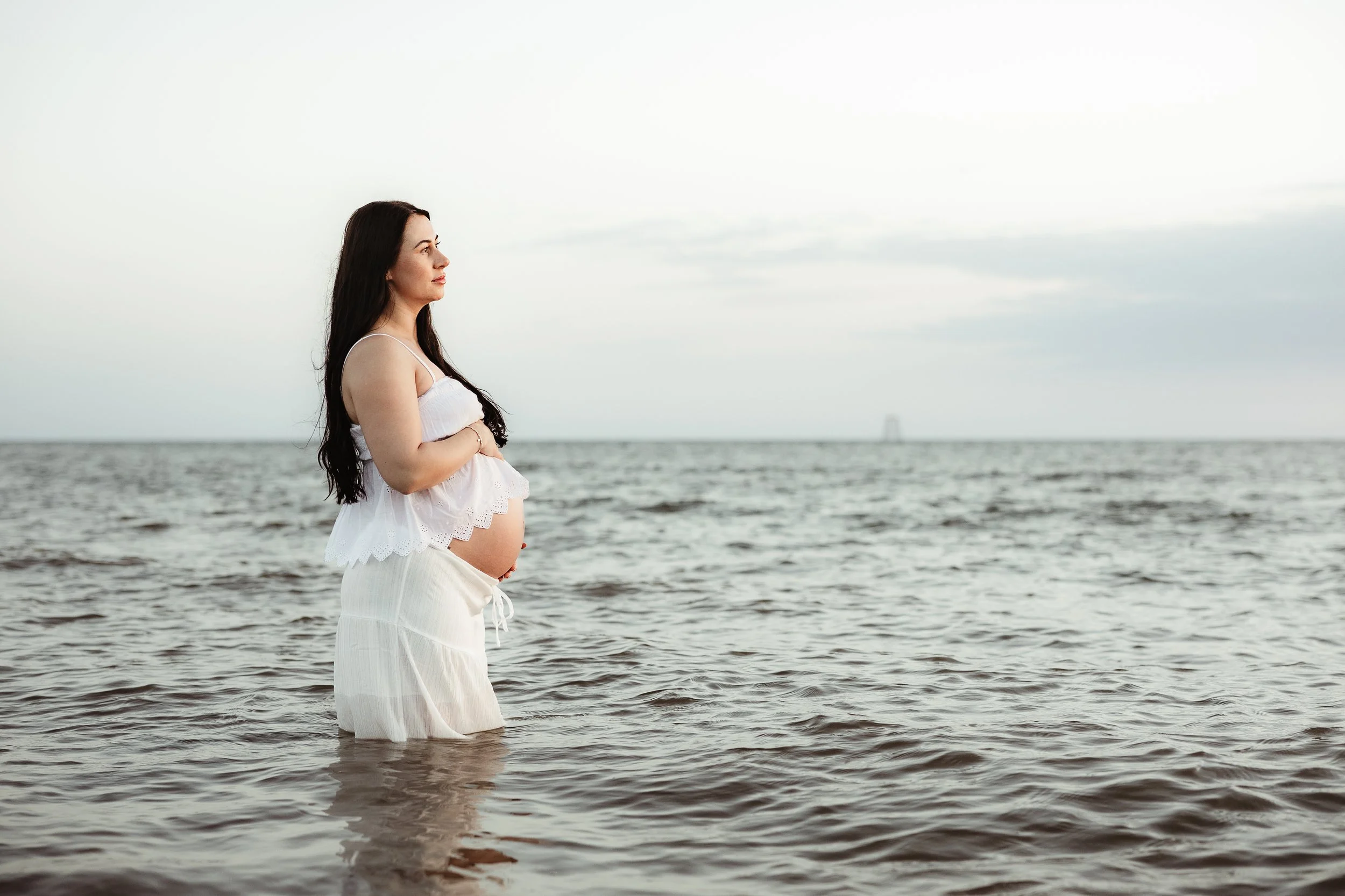 A mother-to-be taking a quiet moment to connect with her baby bump during a natural maternity photography session.