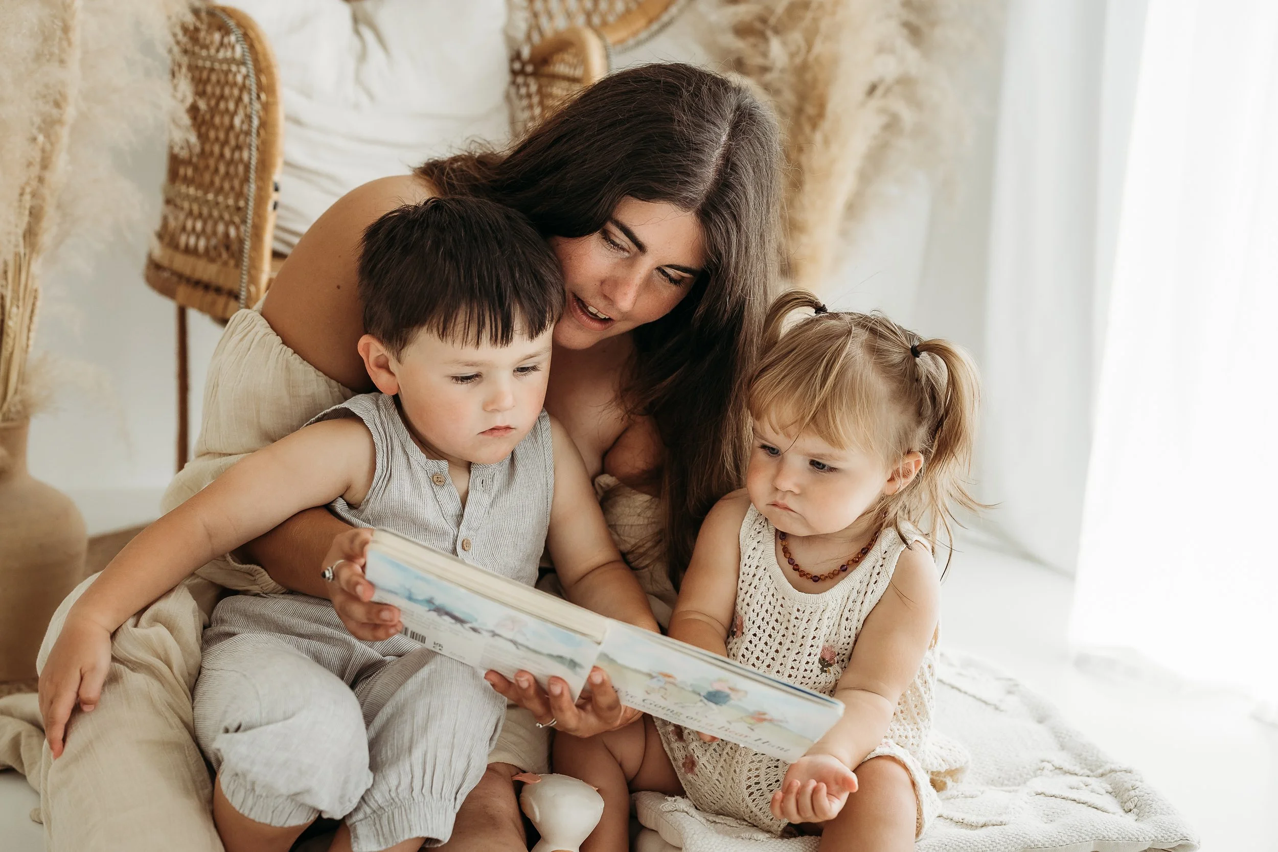 A mother sharing a quiet story time moment with her children at home, capturing the love, connection and little moments of family life.