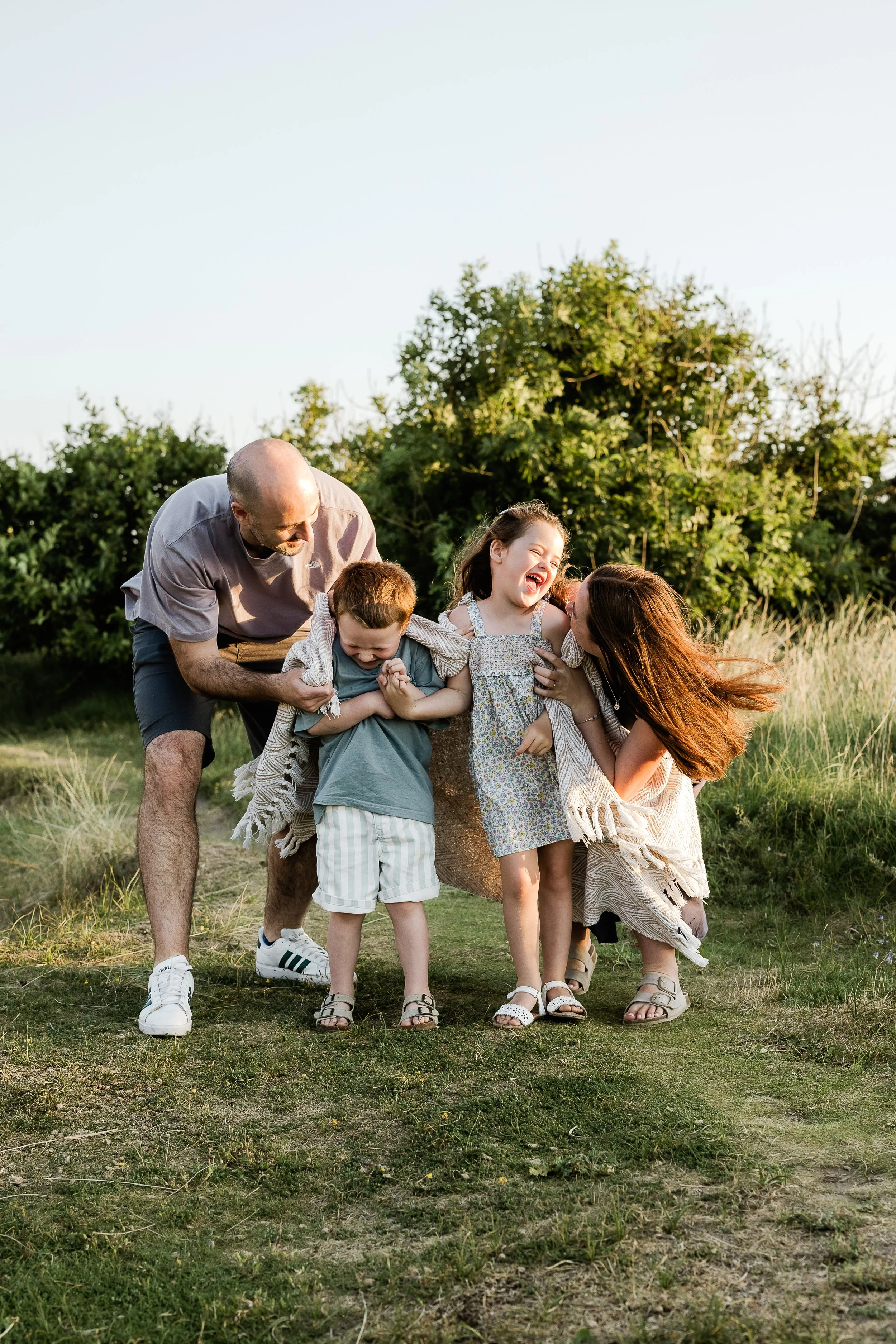 Family of five playing together during a relaxed outdoor family photography session.