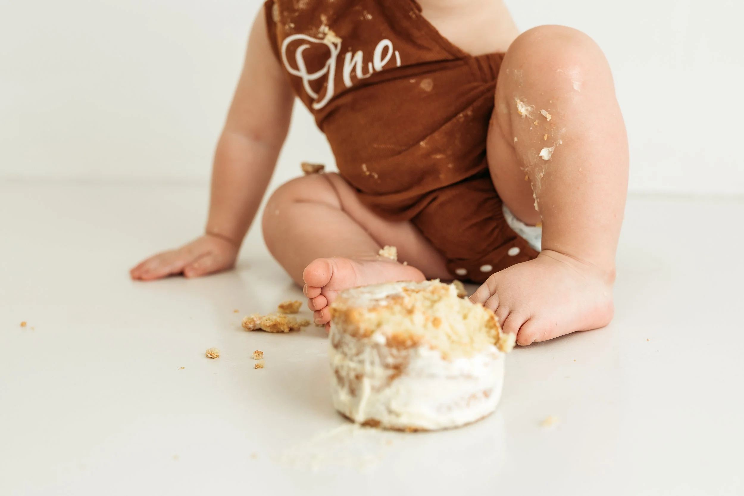 Baby enjoying a messy cake smash during a relaxed first birthday photography session.