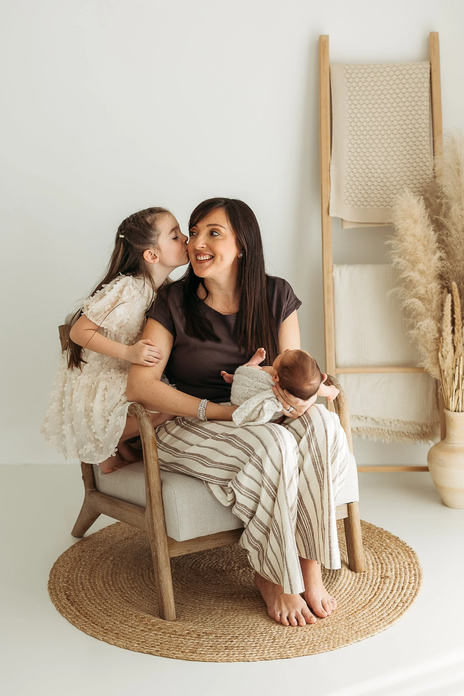 Mother cuddling her children during a relaxed newborn family photography session.