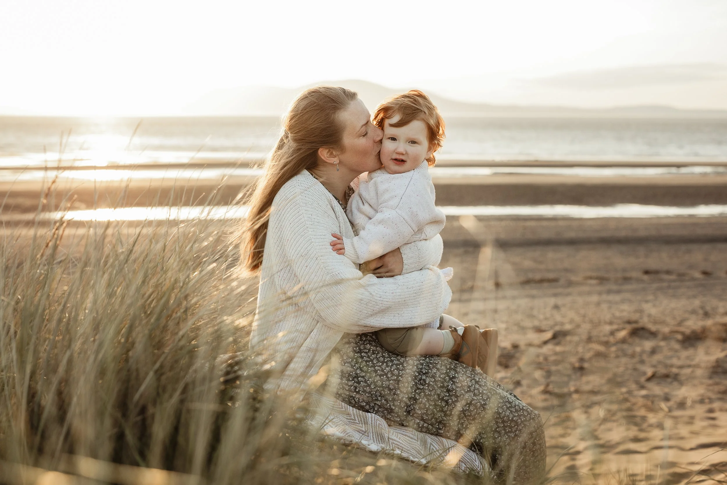 A mother and child enjoying a beautiful beach moment together, capturing the closeness, affection and everyday love that makes childhood so special.