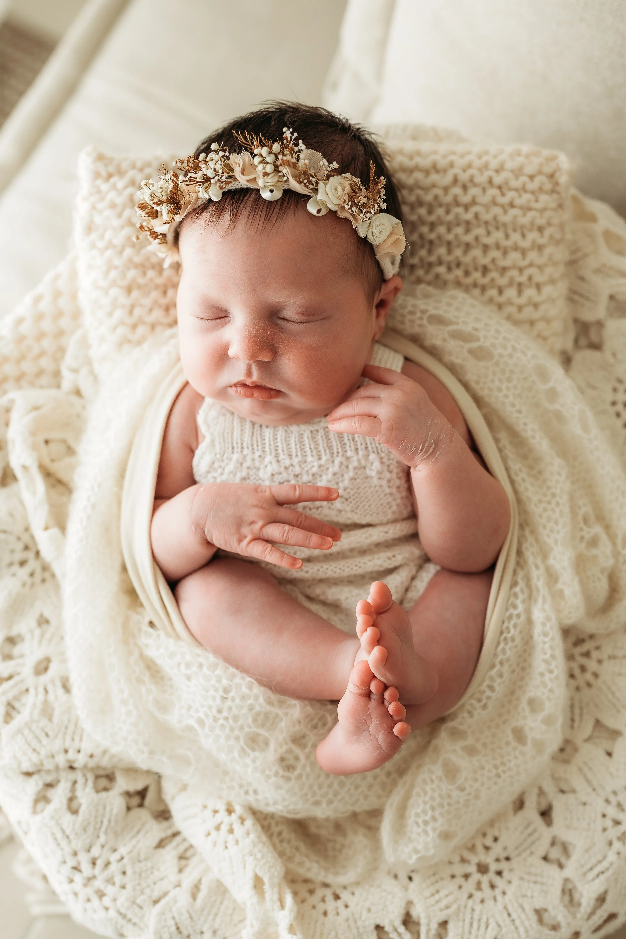 Newborn baby sleeping peacefully on a soft knitted blanket.