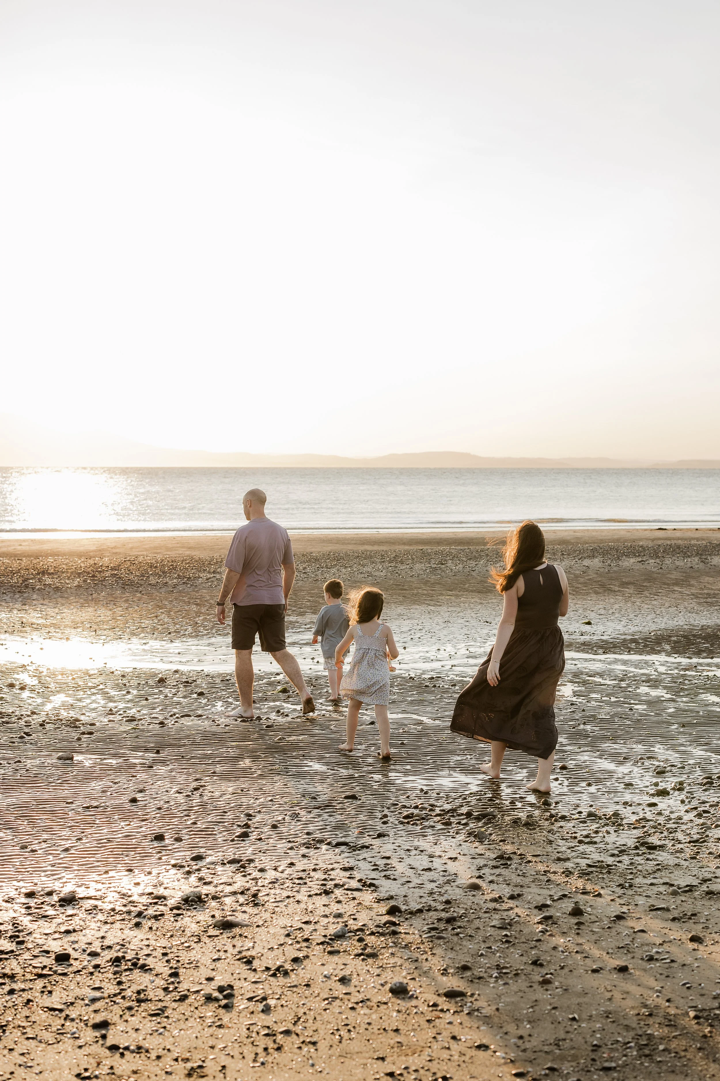 Family of five walking together on Silloth West Beach at sunset.