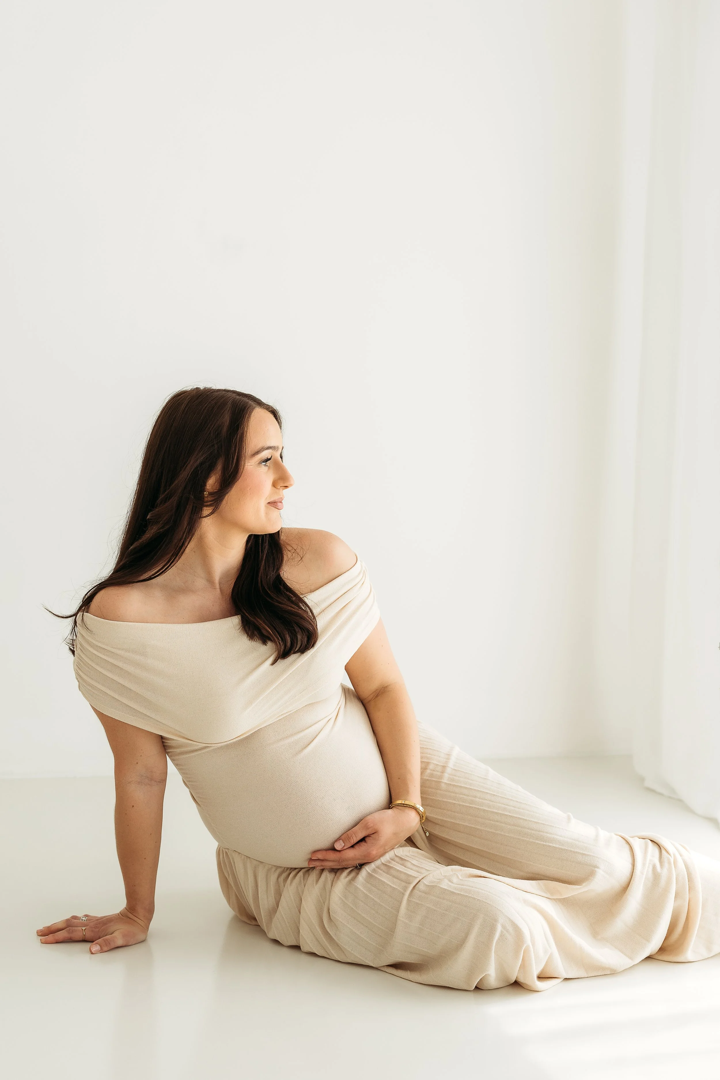 Pregnant woman celebrating her bump during a relaxed natural light studio maternity session.