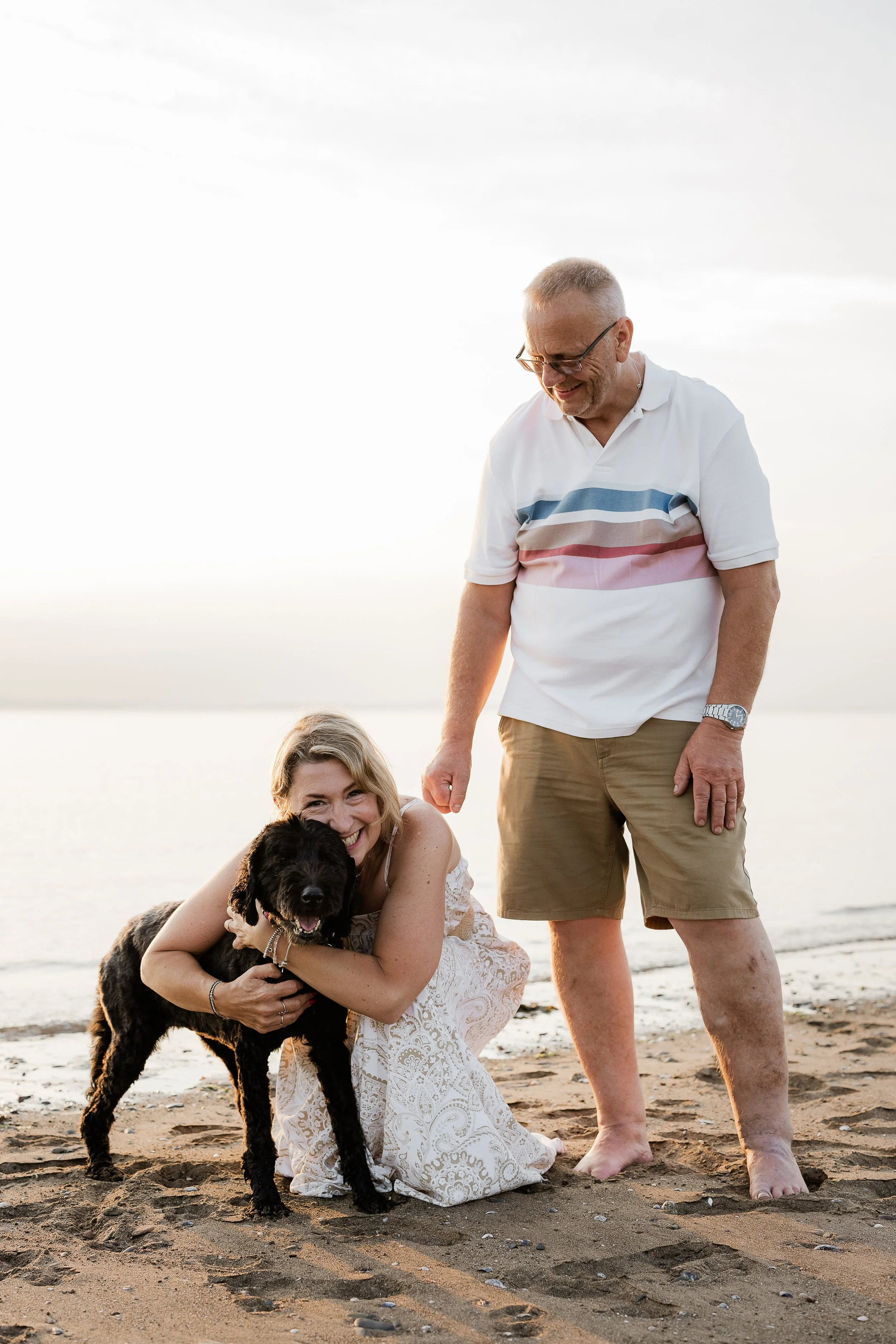 A couple enjoying a quiet beach moment with their dog, during an extended family session.