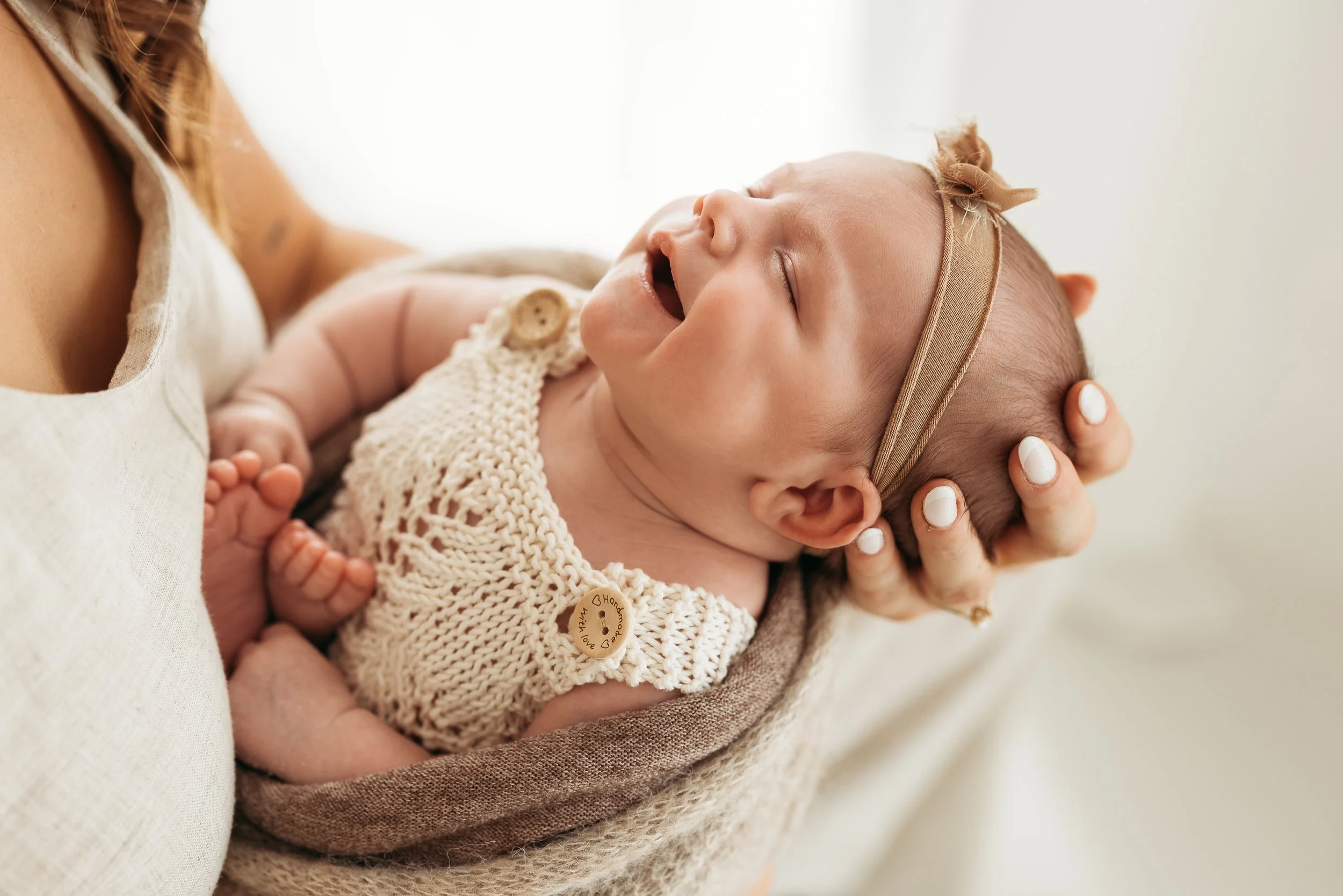 Close-up of a newborn baby being gently cradled during a newborn photography session.