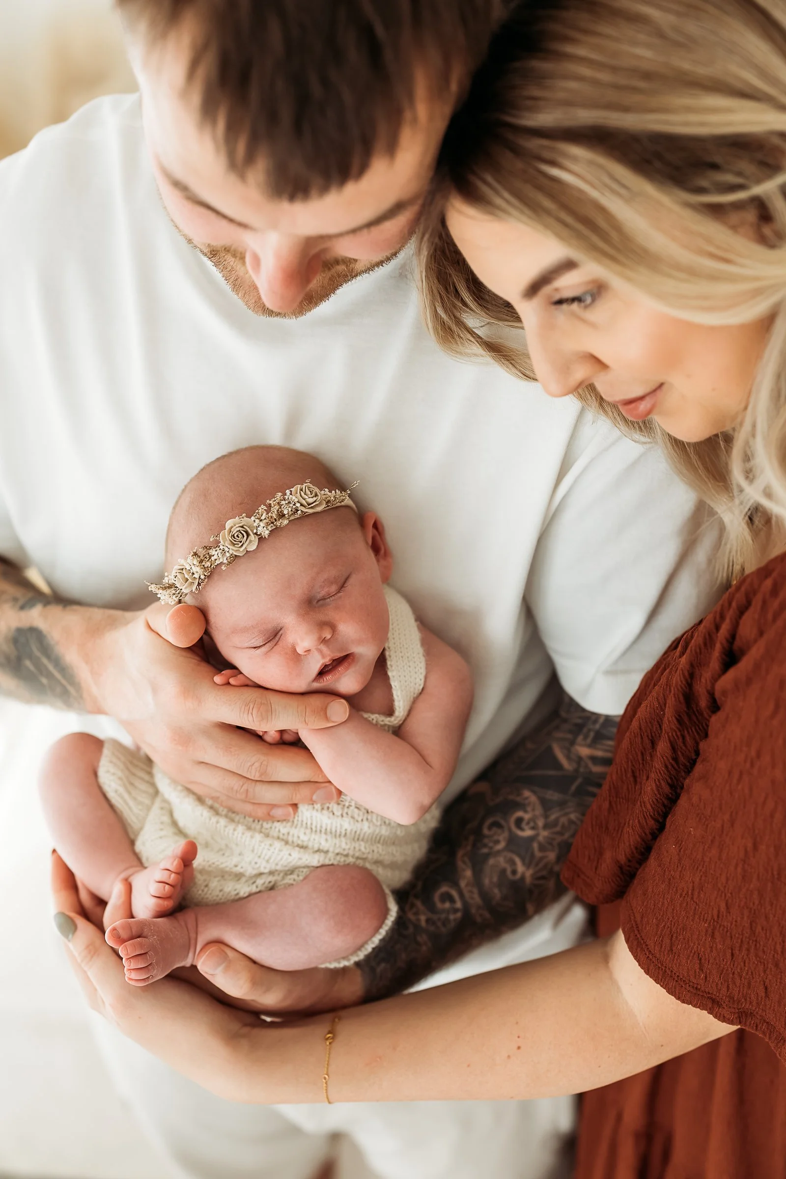 Parents lovingly holding their newborn baby during a connection-focused newborn photography session.