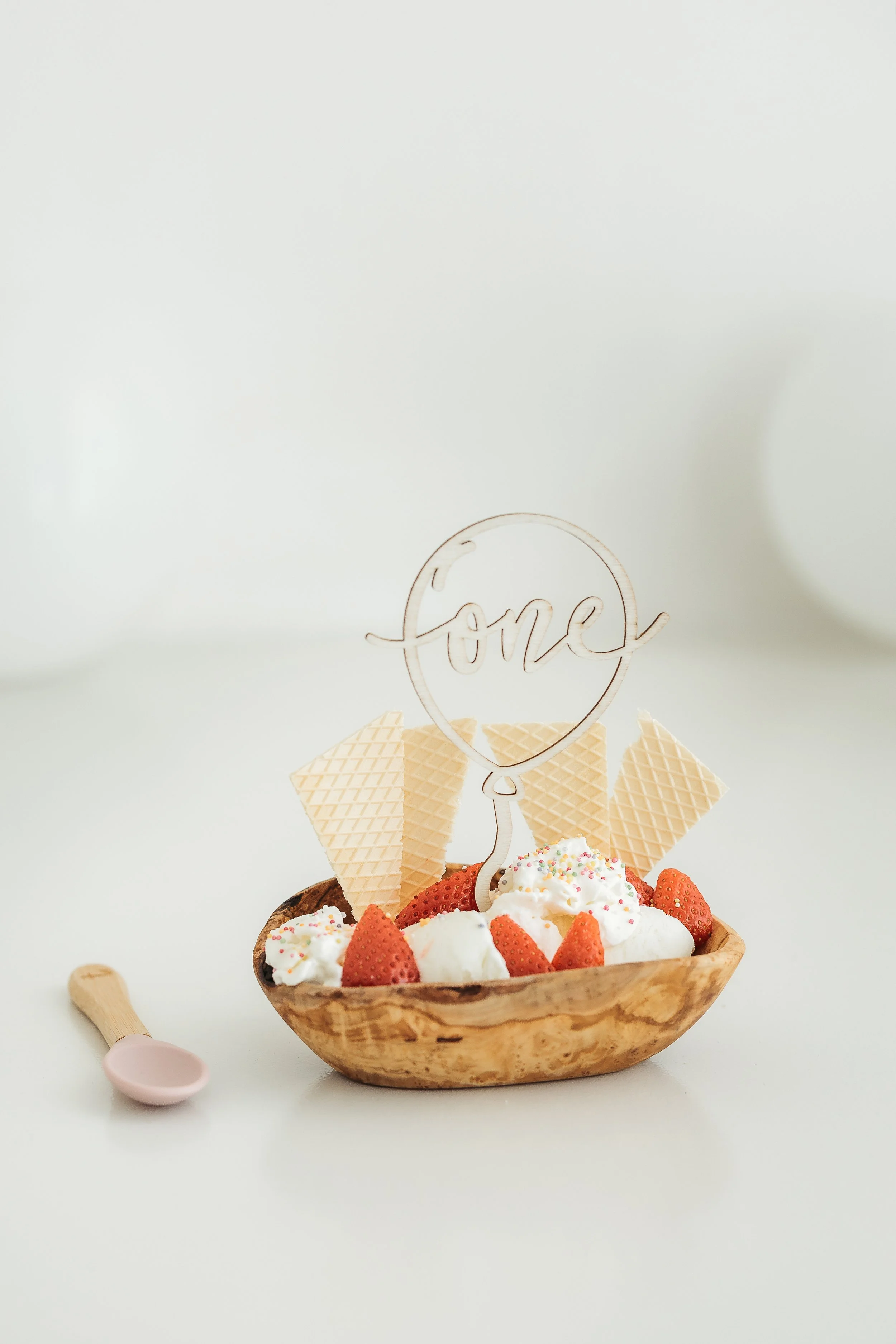 Ice cream dessert decorated with strawberries, sprinkles and a number one topper for a first birthday celebration