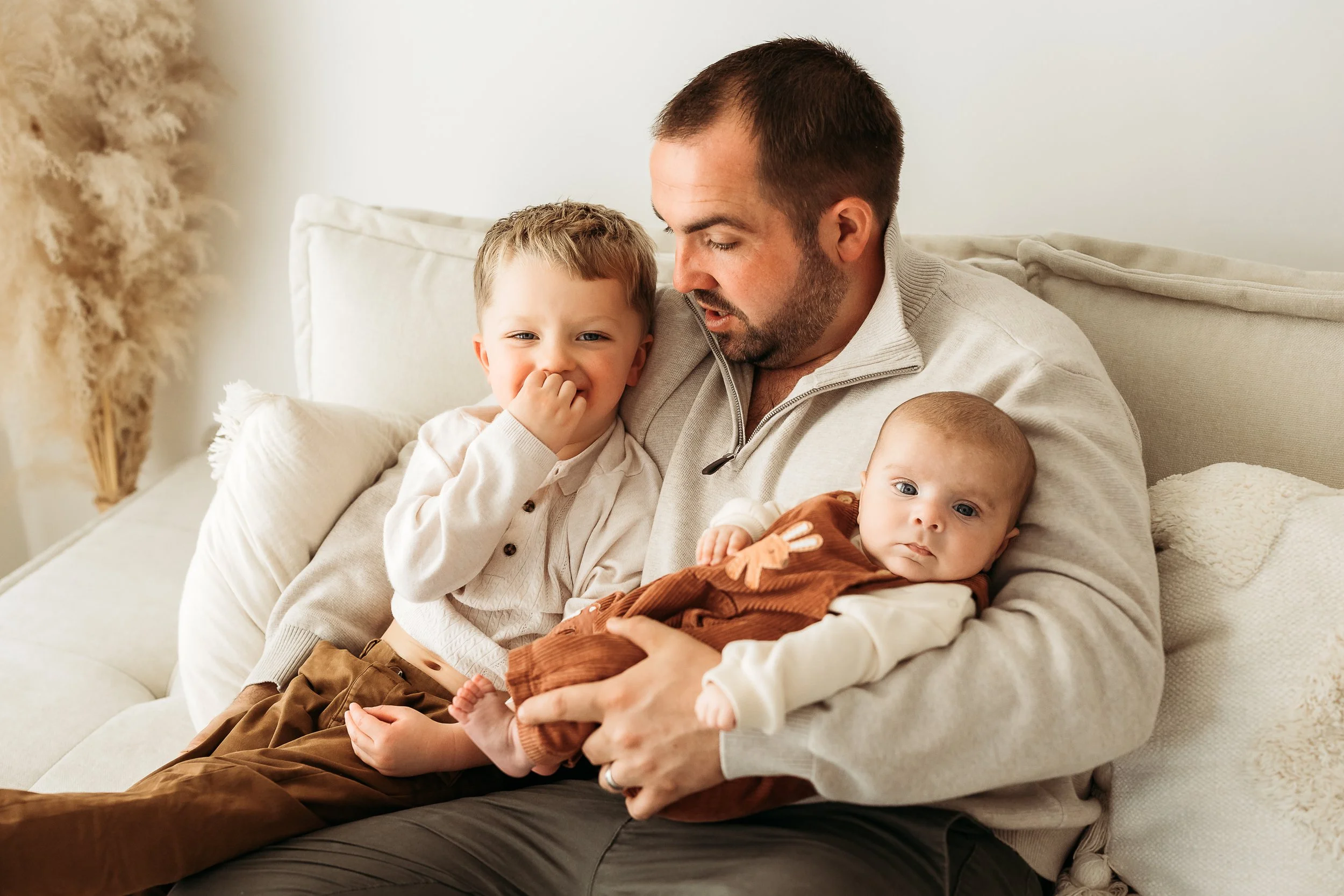 A father sharing a quiet moment with his two children, surrounded by cuddles, connection and the everyday moments that become treasured memories.