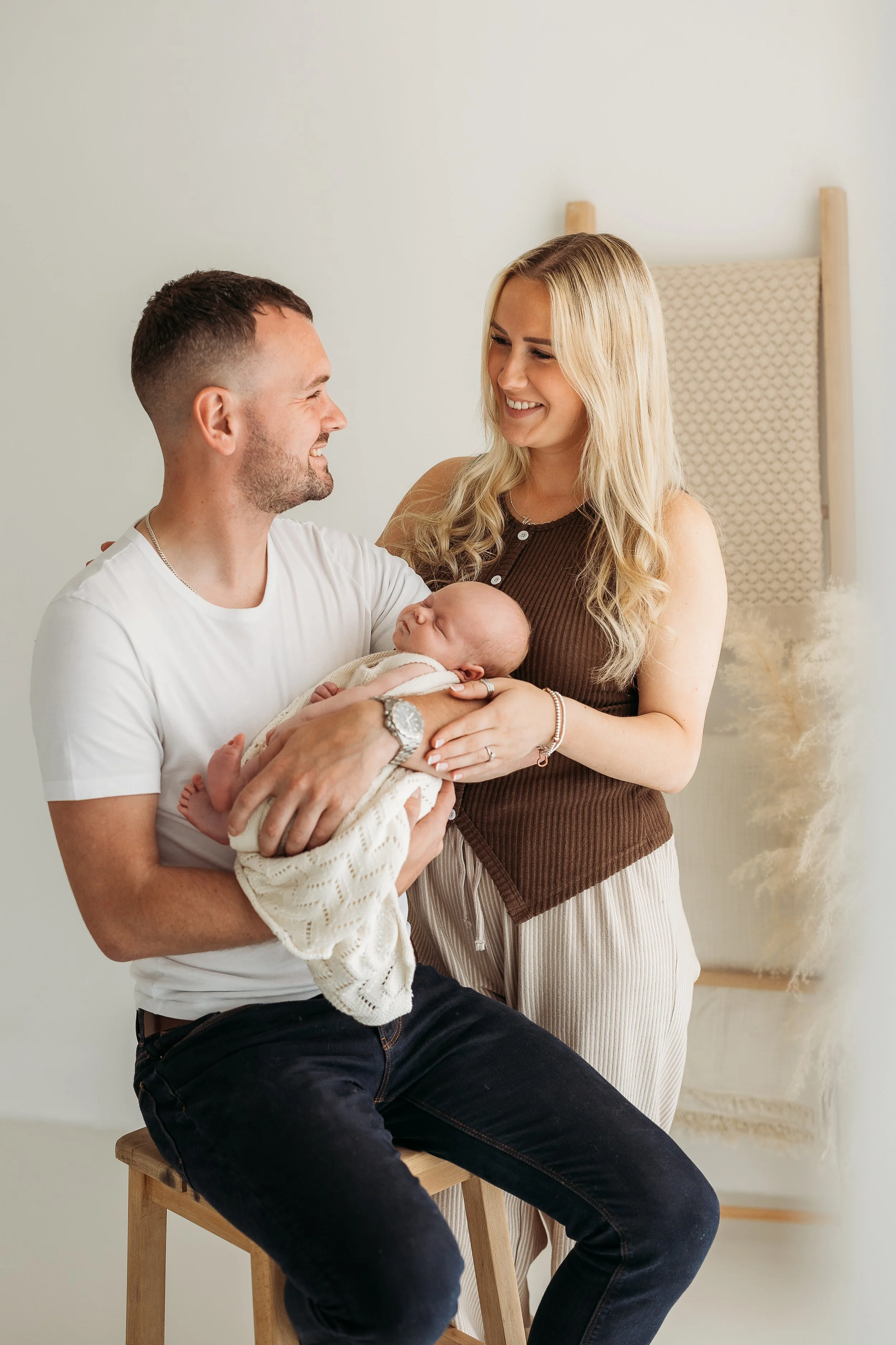 Parents holding their newborn baby together during a relaxed studio newborn photography session.