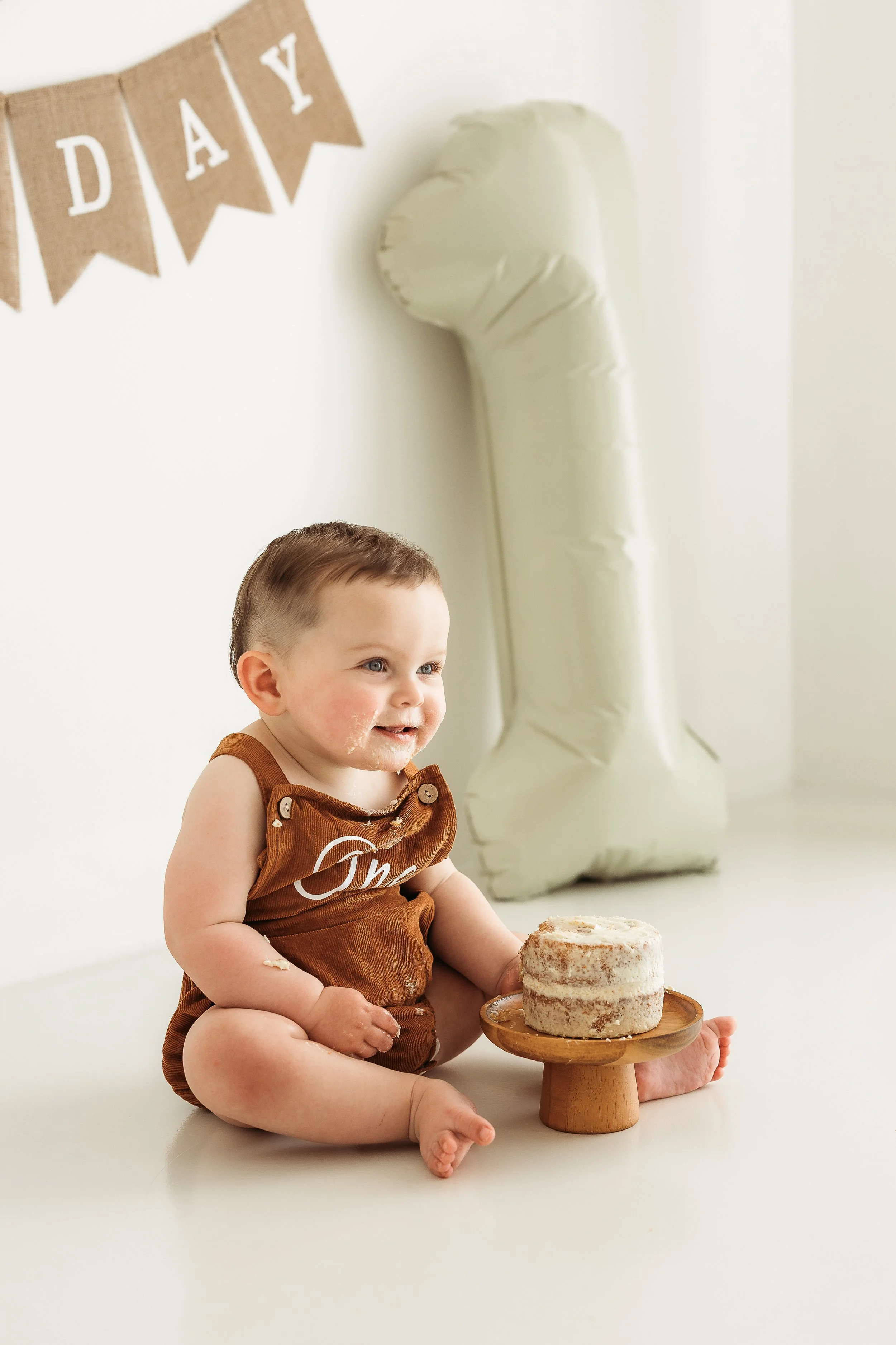 One-year-old celebrating their first birthday with a relaxed cake smash photography session.