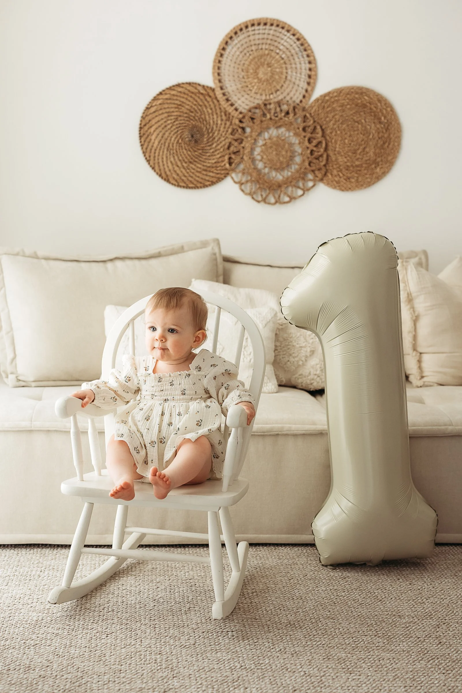 Baby sitting in a wooden chair during a relaxed first birthday studio session.