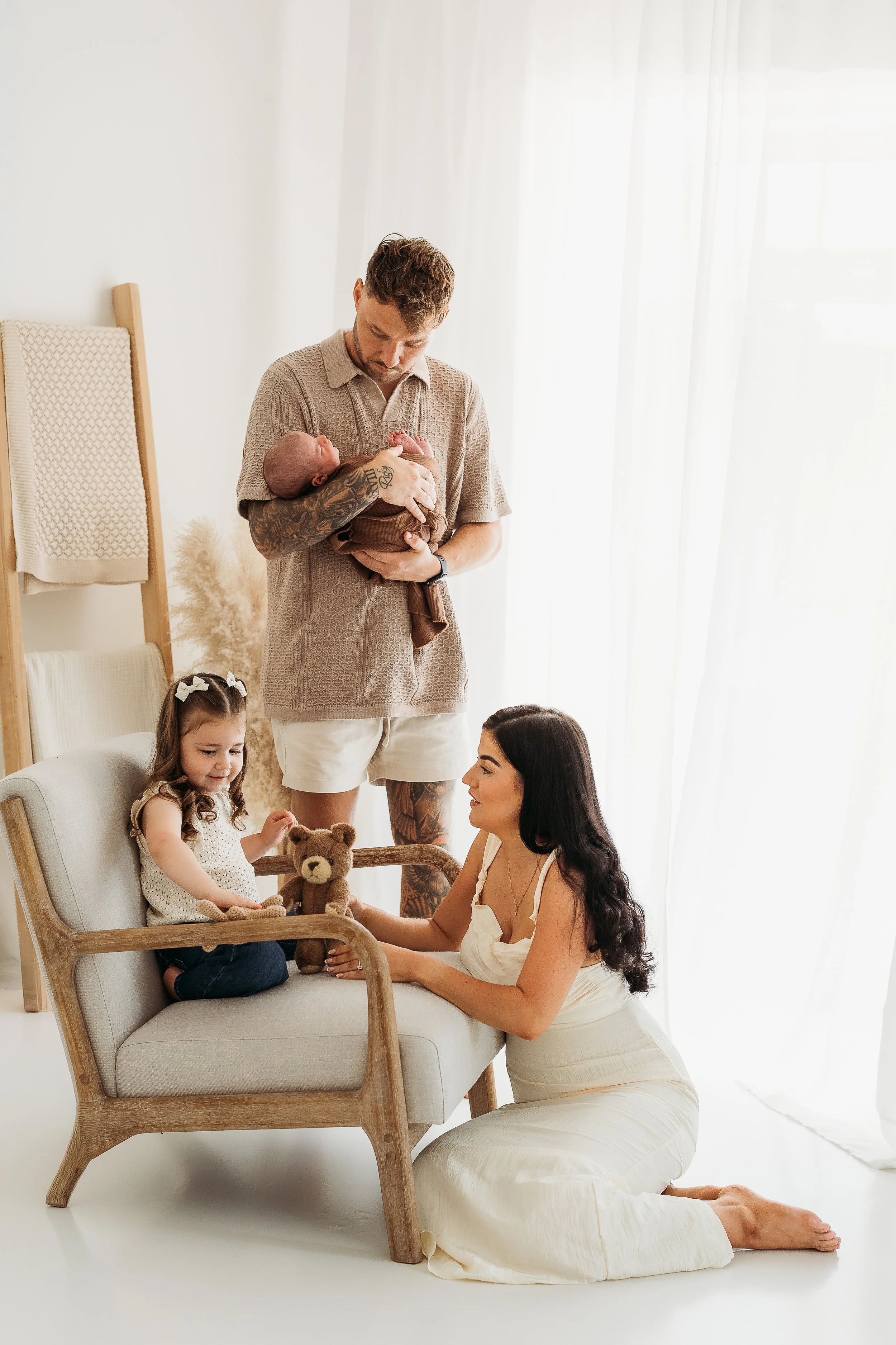 Parents and sibling connecting with their newborn baby during a natural family newborn photography session.