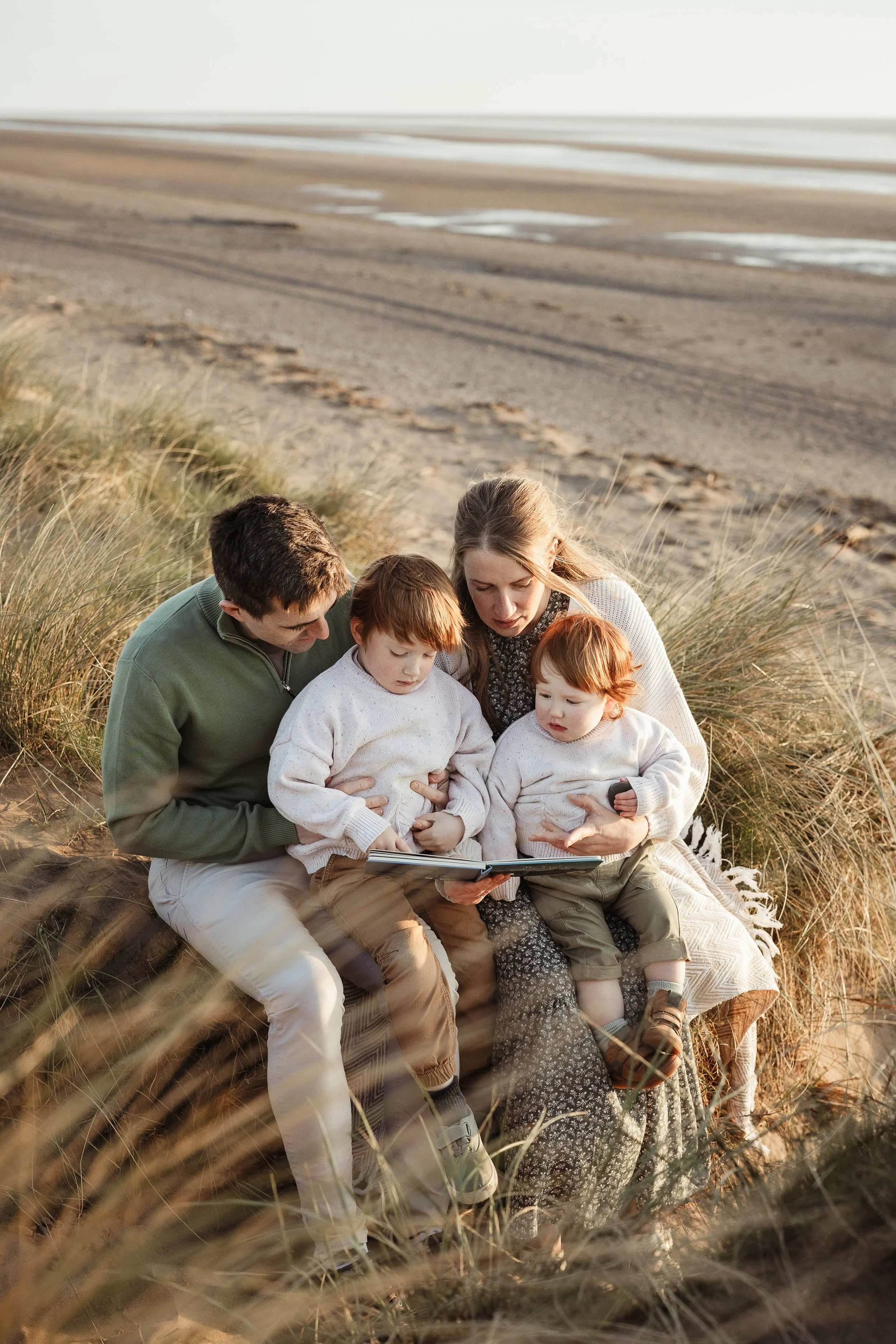 Family of five sitting together on Silloth West Beach during a relaxed family photography session.