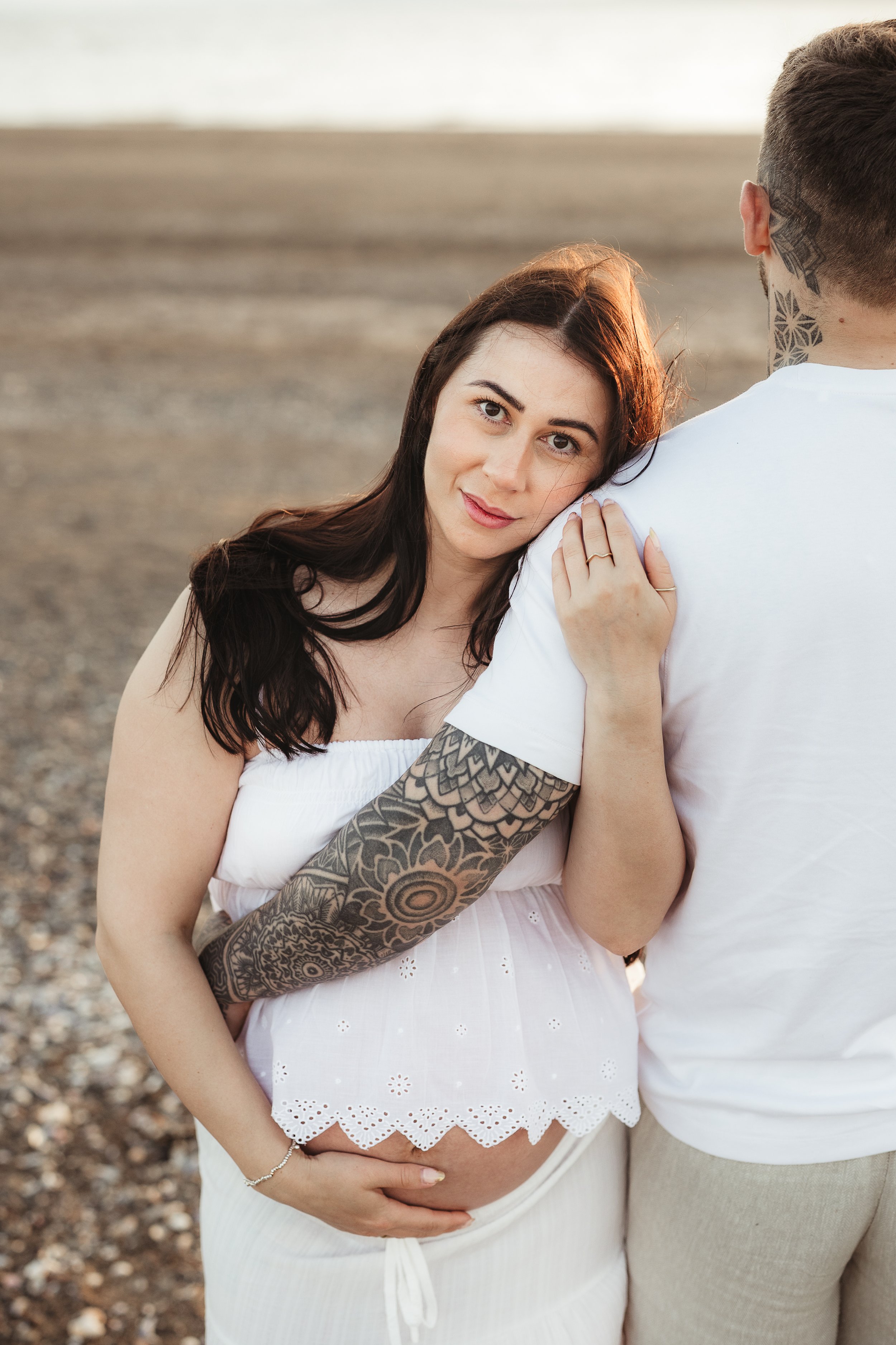 Expecting parents sharing a gentle embrace during an outdoor maternity photography session.