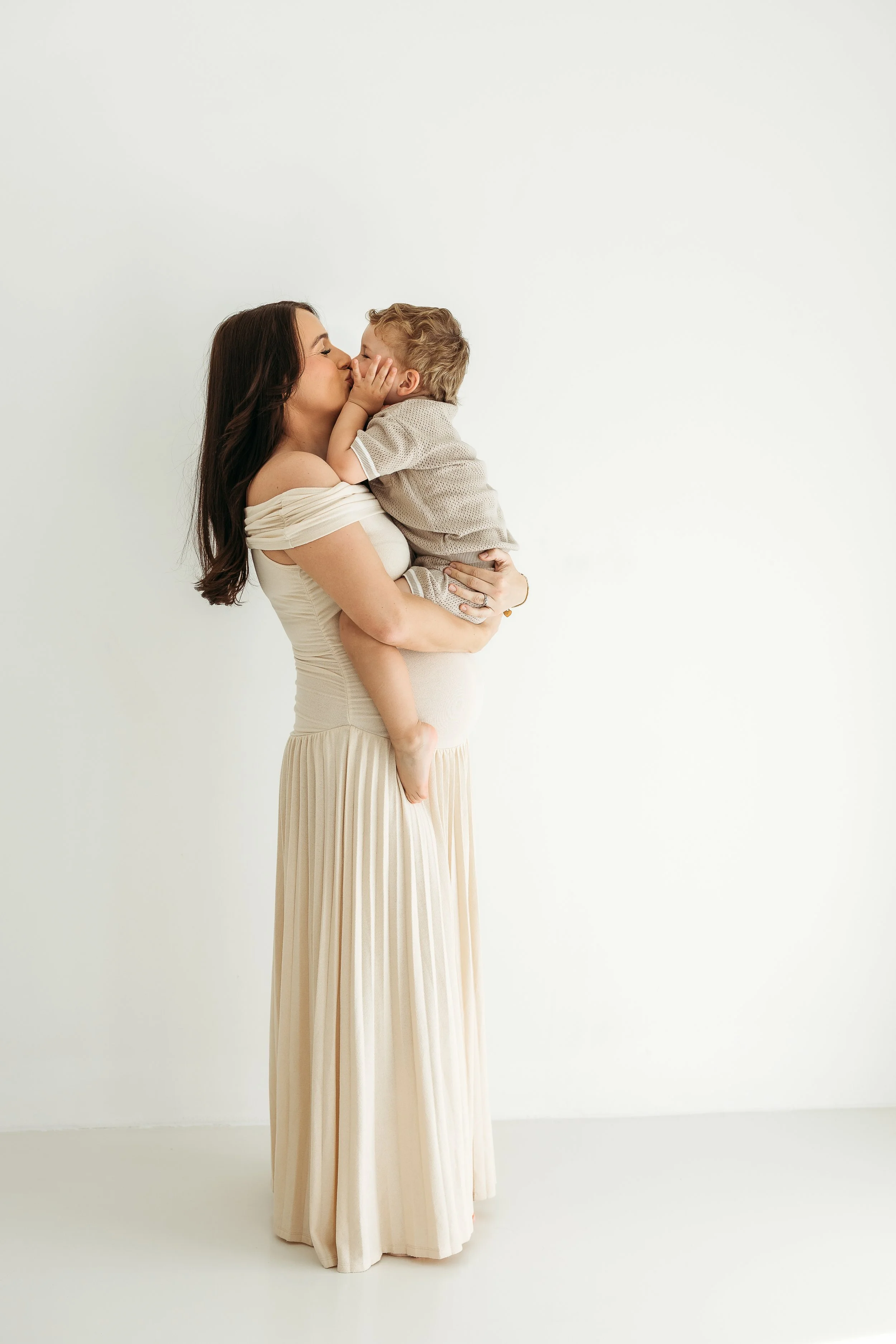A mother and young son sharing a loving connection during a maternity photography session before becoming a bigger family.
