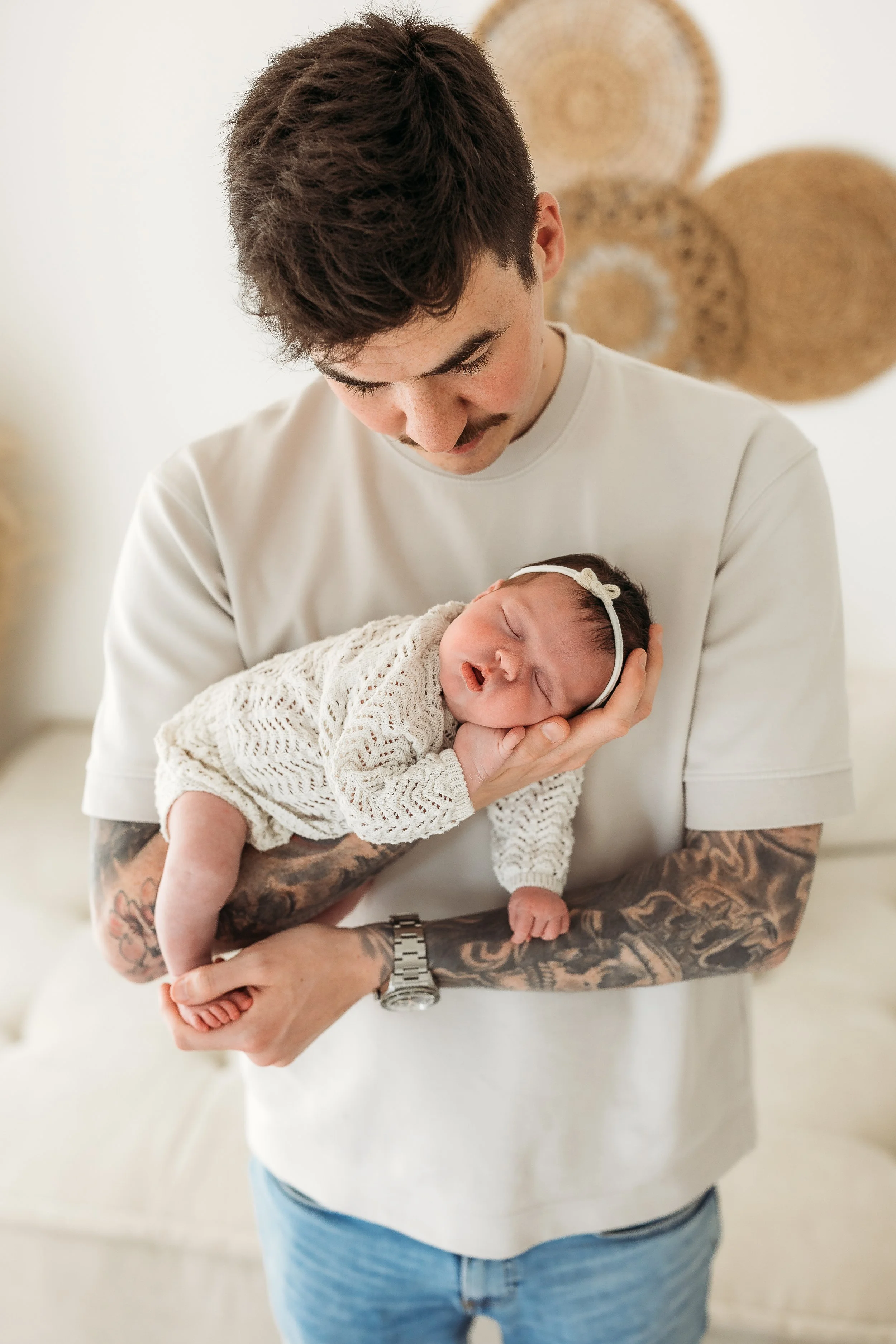 Father cuddling his sleeping newborn baby during a natural newborn photography session.