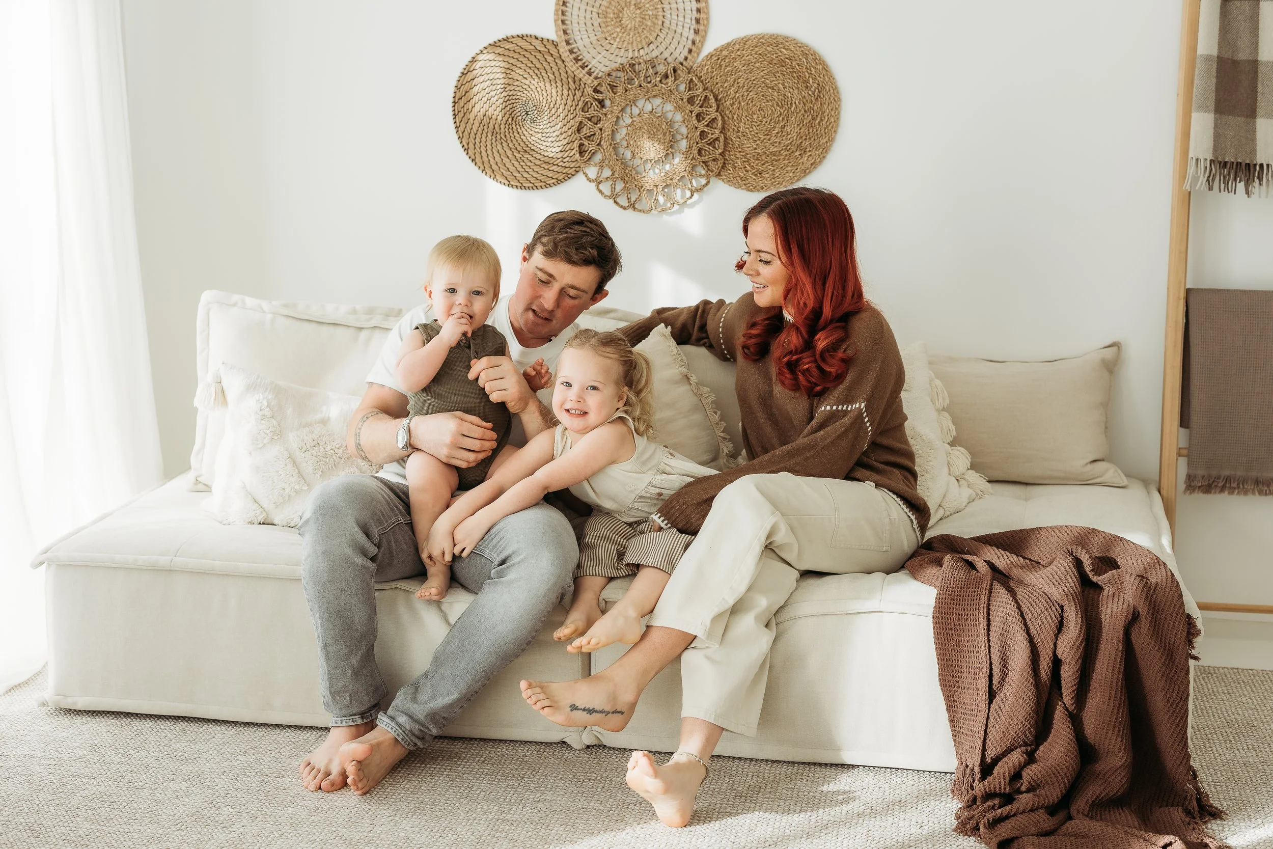 Family of four sharing a relaxed moment together on a sofa during a first birthday photography session at home