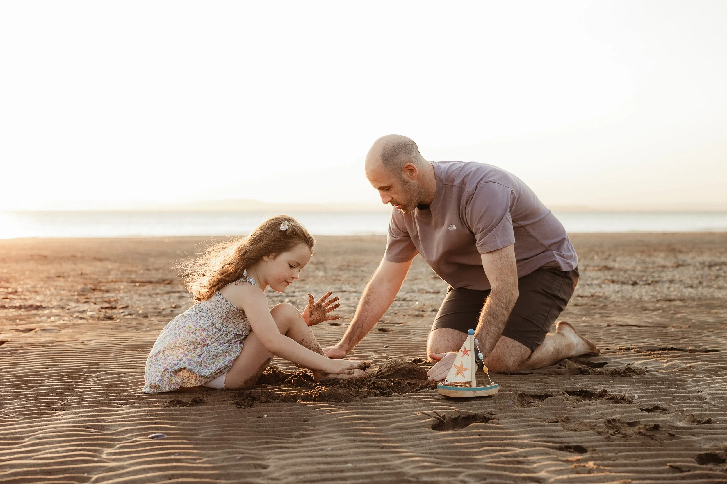 A father and daughter exploring the beach together, creating memories through play, curiosity and little adventures.