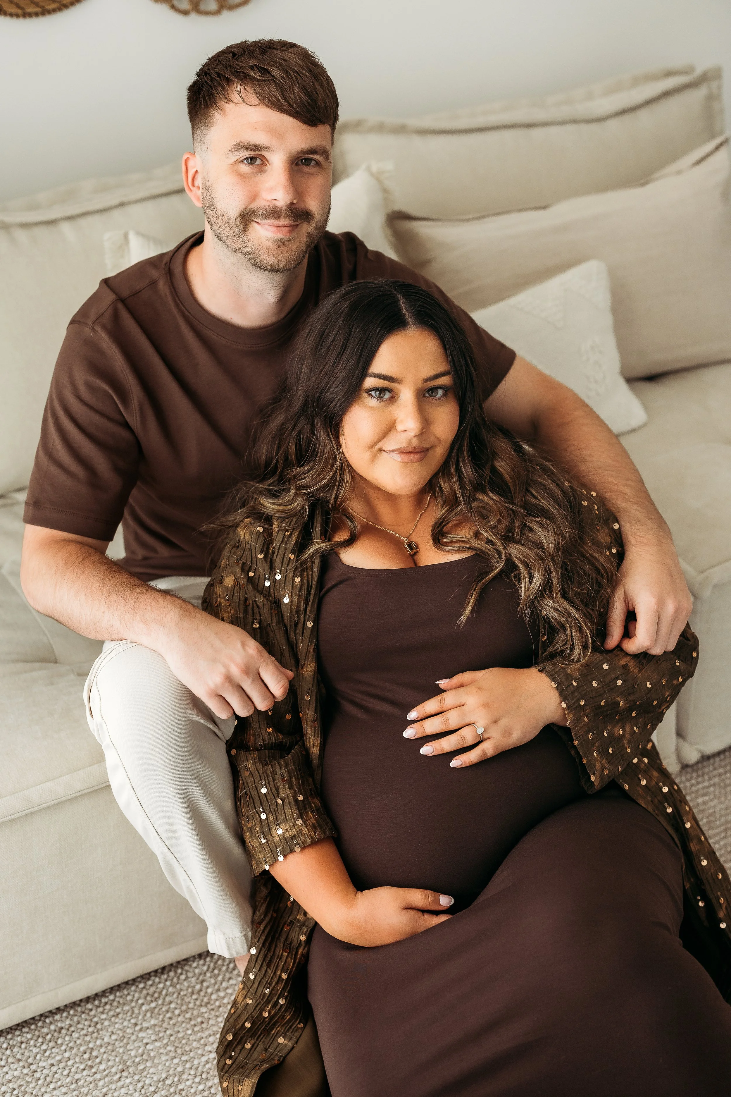Expecting parents sharing a relaxed moment together during a lifestyle maternity photography session, celebrating their growing family.