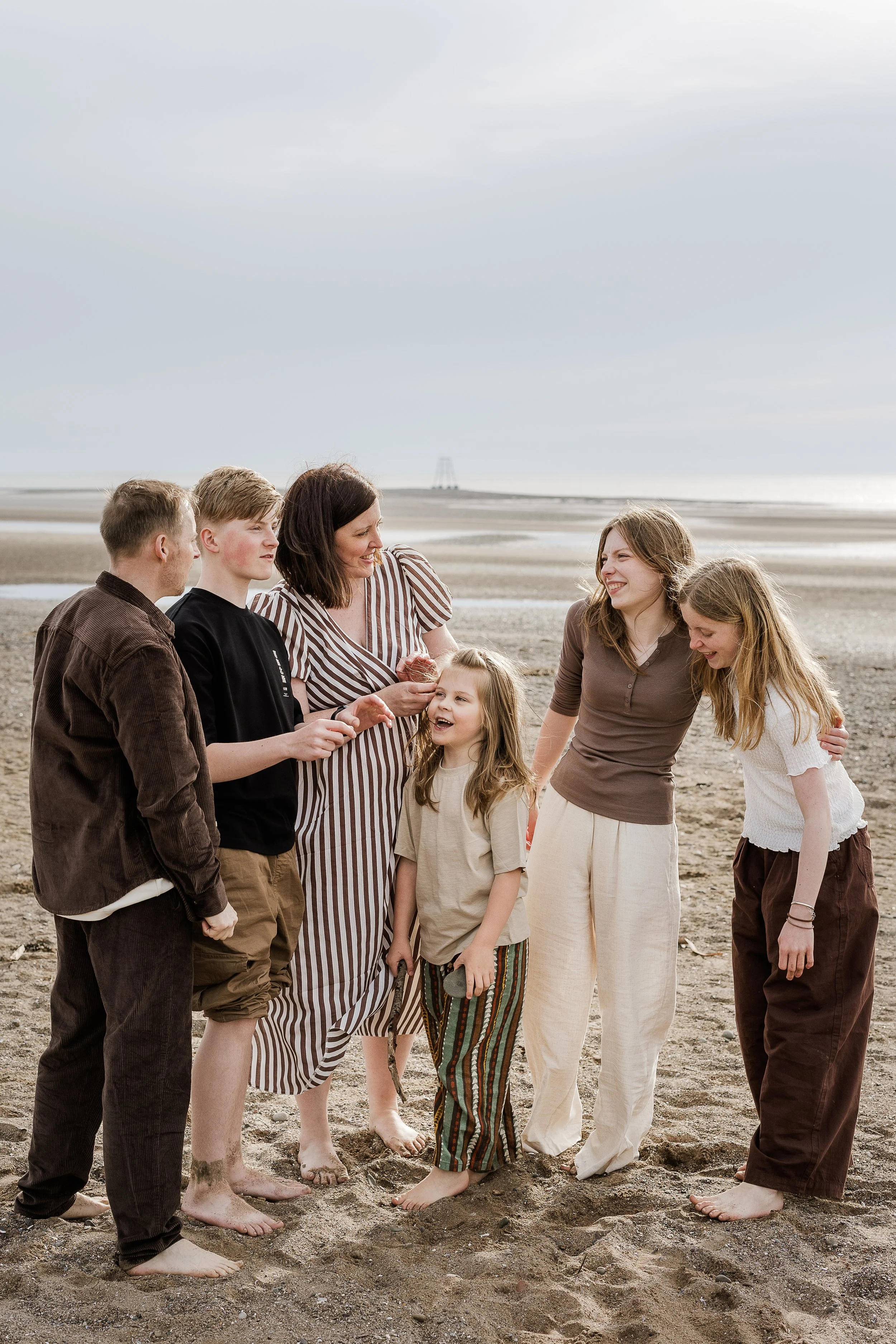 Family laughing together during a relaxed beach photography session.