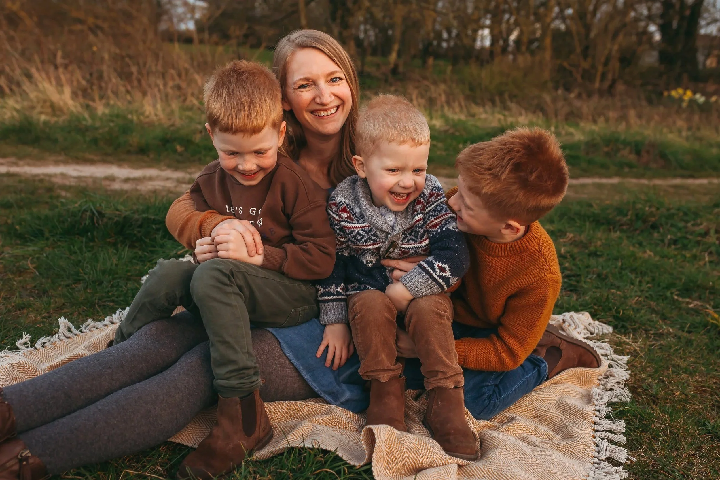 Ines Henderson with her three sons, laughing and cuddling together outdoors at sunset.