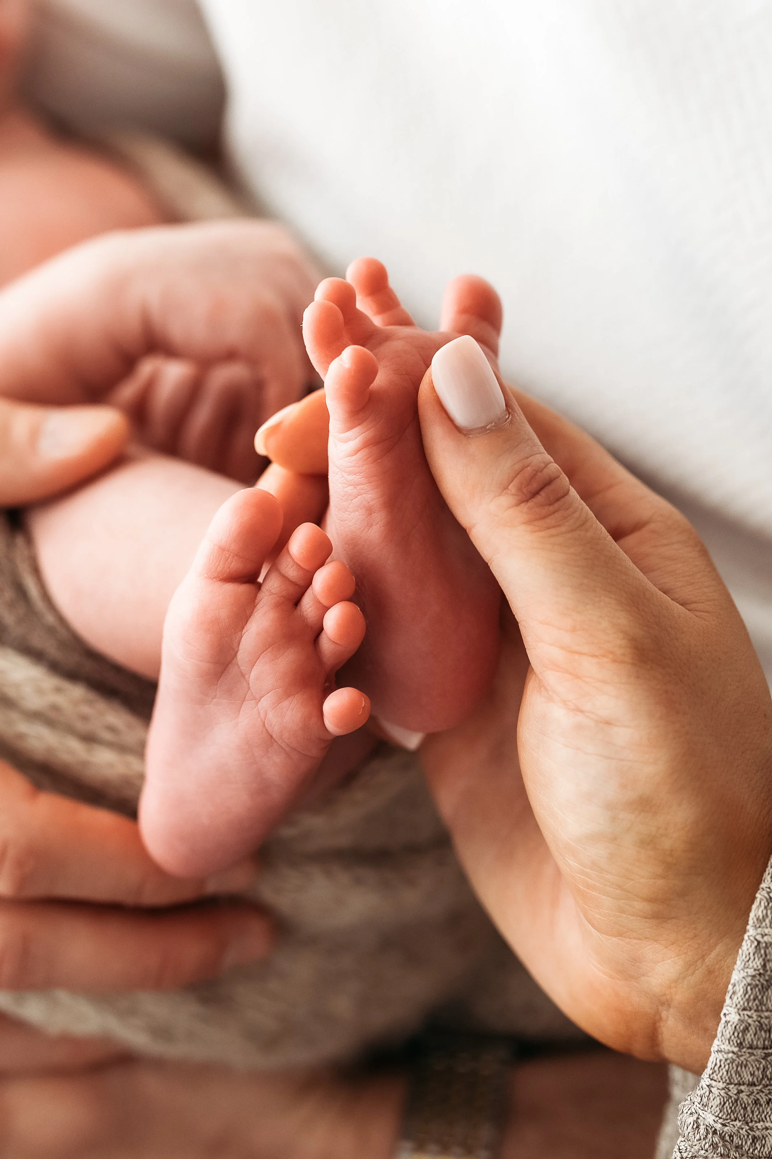 Close-up of a parent gently holding their newborn baby’s hand during a connection-focused newborn photography session.